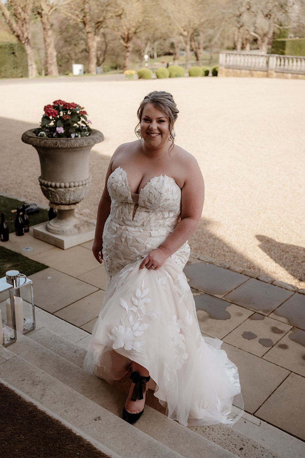 a bride on her wedding day, wearing a white wedding dress, walking up the steps at Hedsor House wedding venue