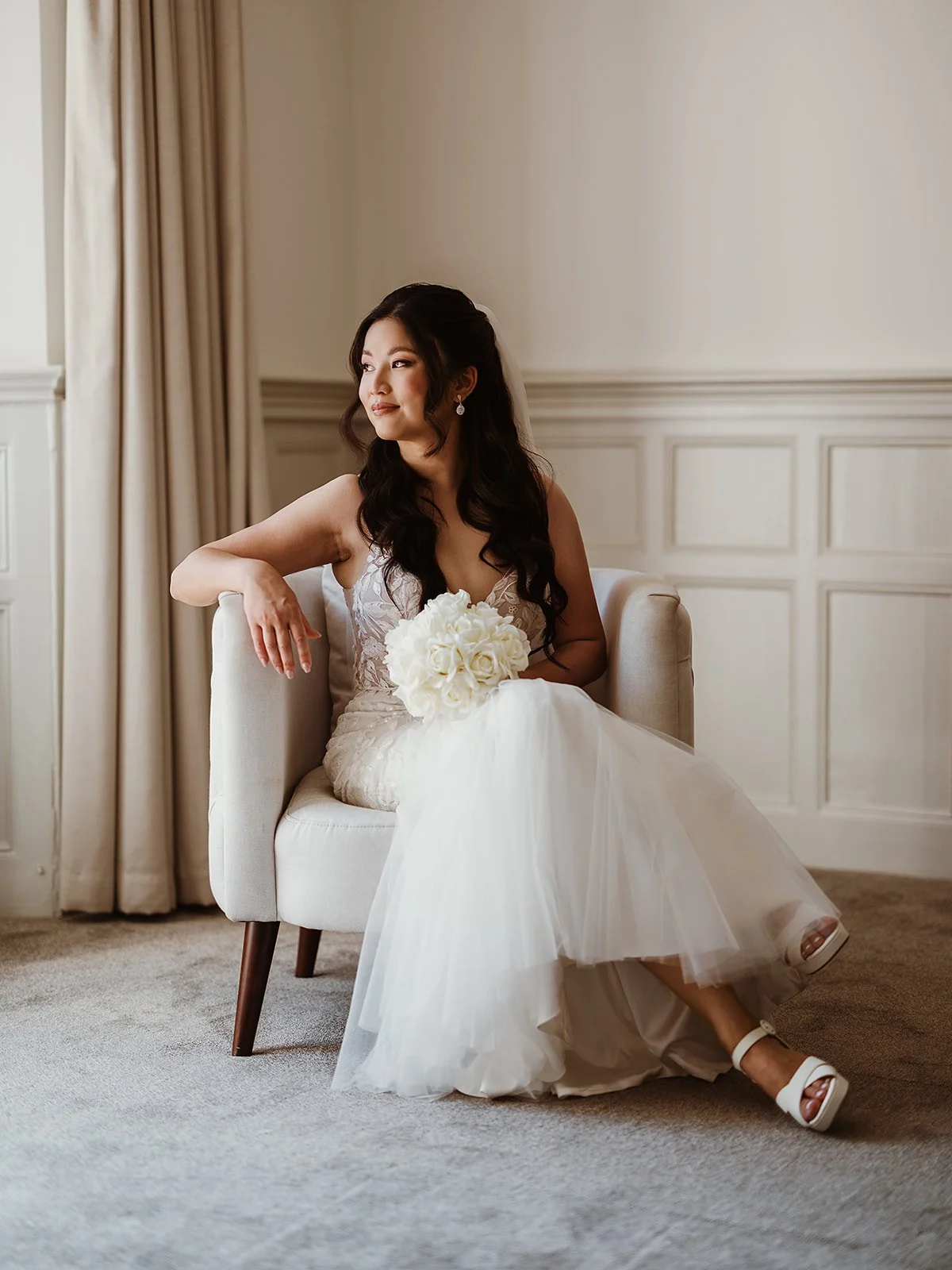 bride on her wedding day, sitting in an armchair and holding her bouquet