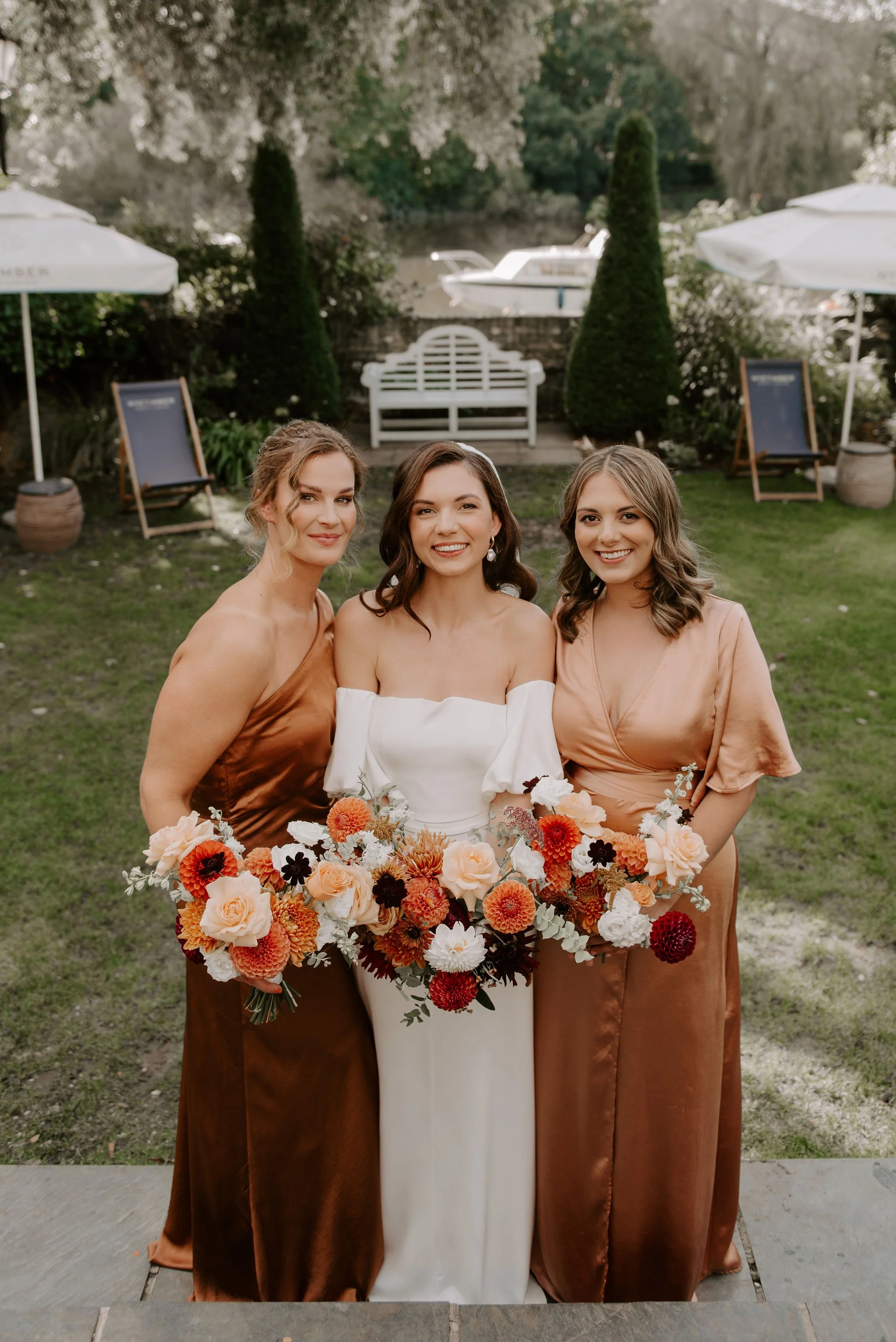 Bride with two bridesmaids, smiling and holding their bouquets