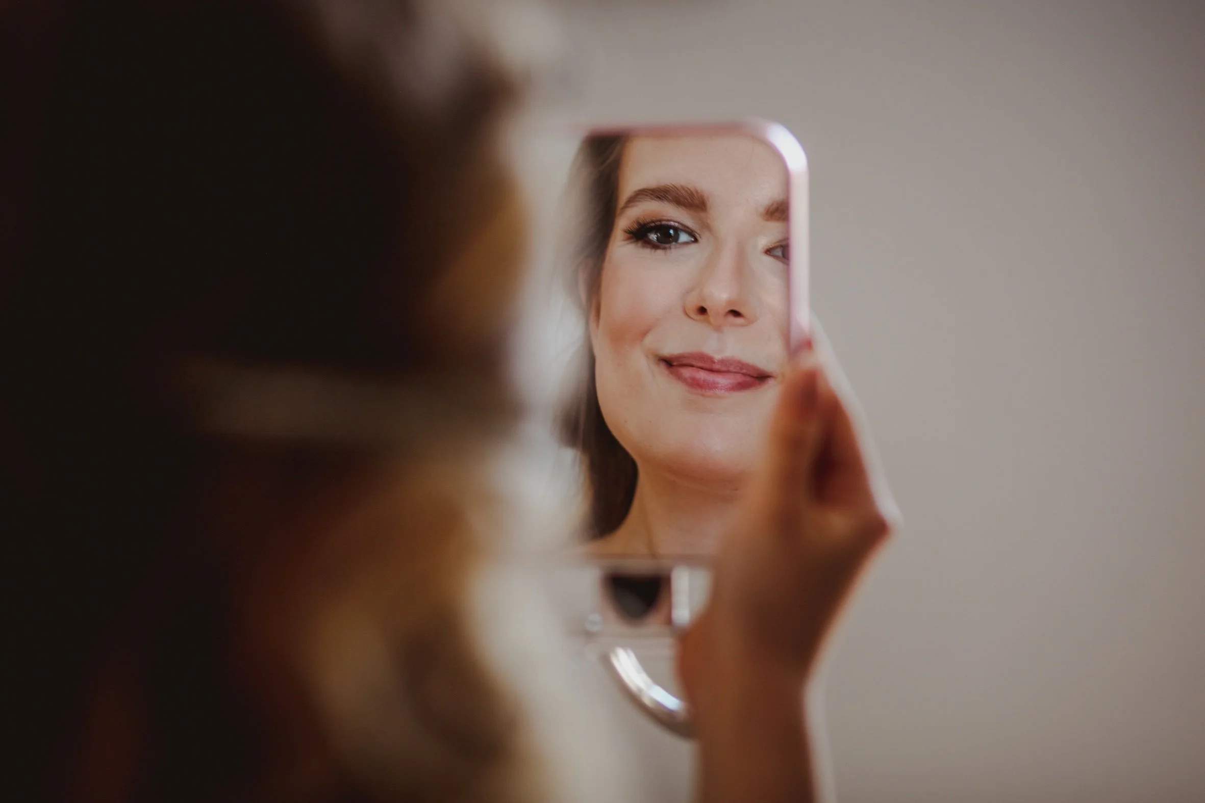 Bride looking at her reflection in the mirror during a bridal makeup lesson