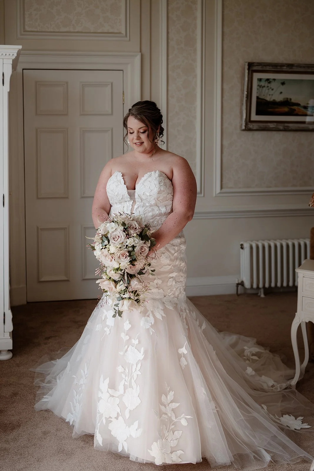 a bride on her wedding day, wearing a white wedding dress and holding a bridal bouquet