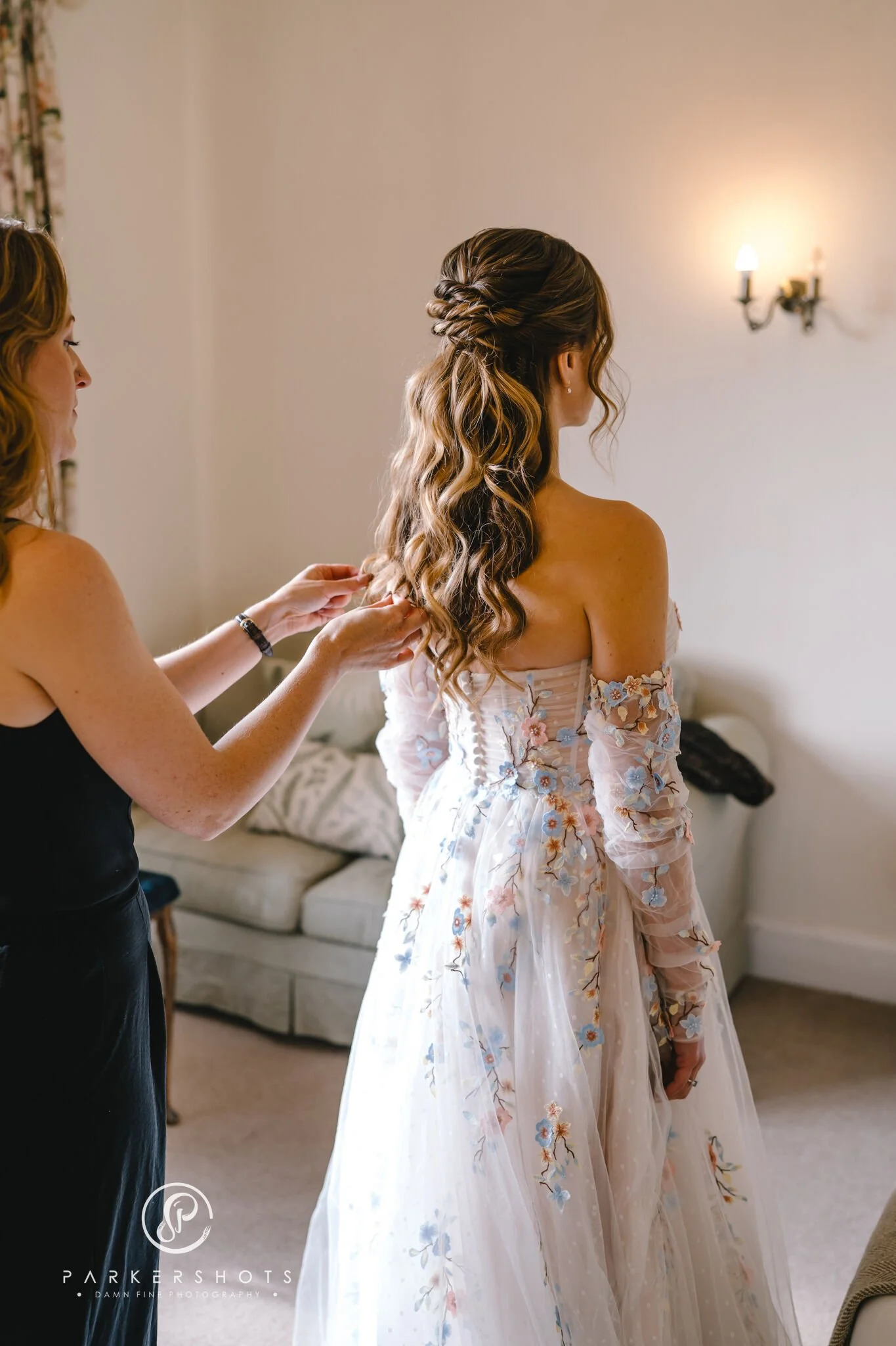 Bridal hair stylist doing final touches on the bride's hair on her wedding day