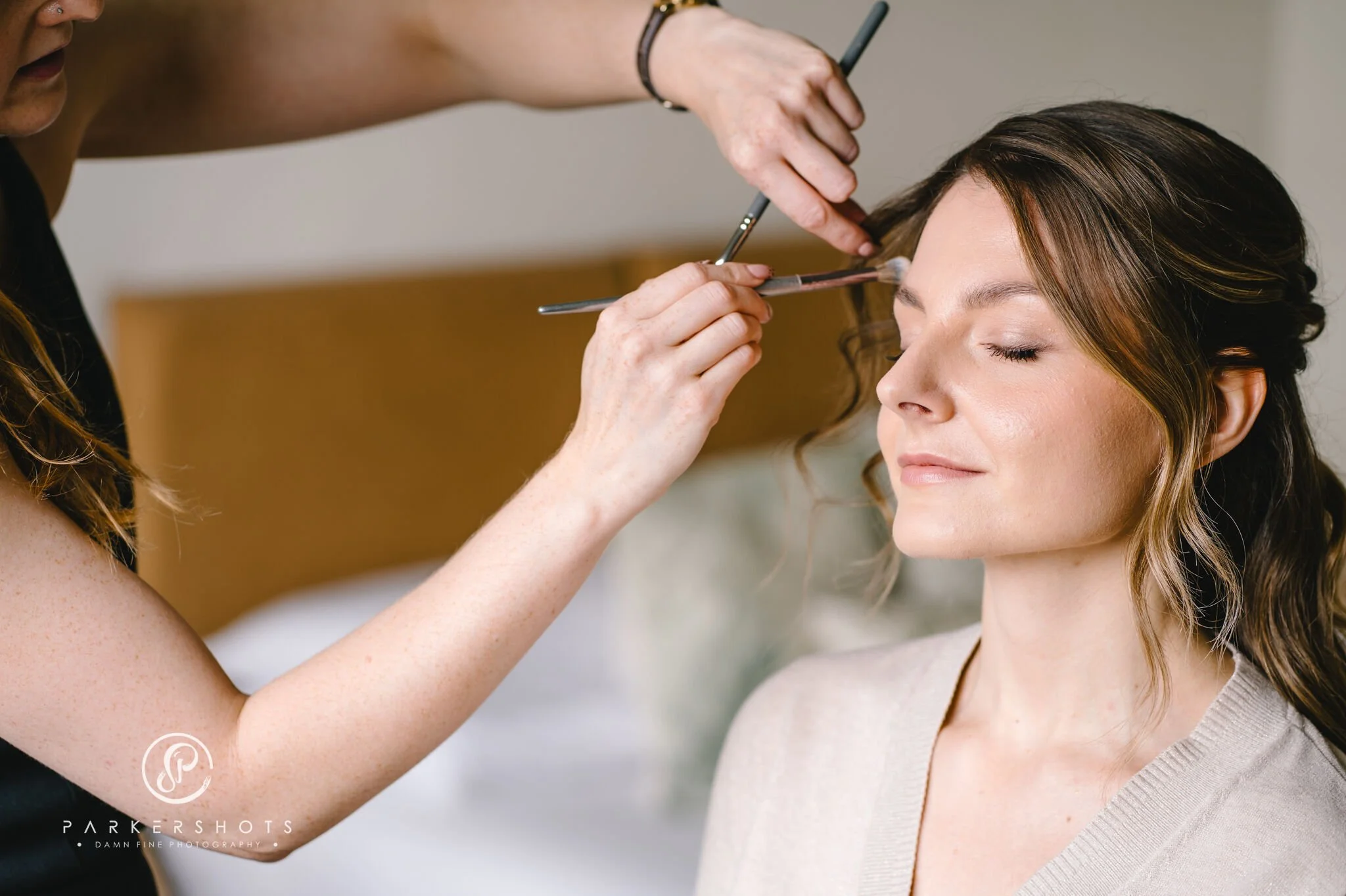 bride having makeup applied on wedding day