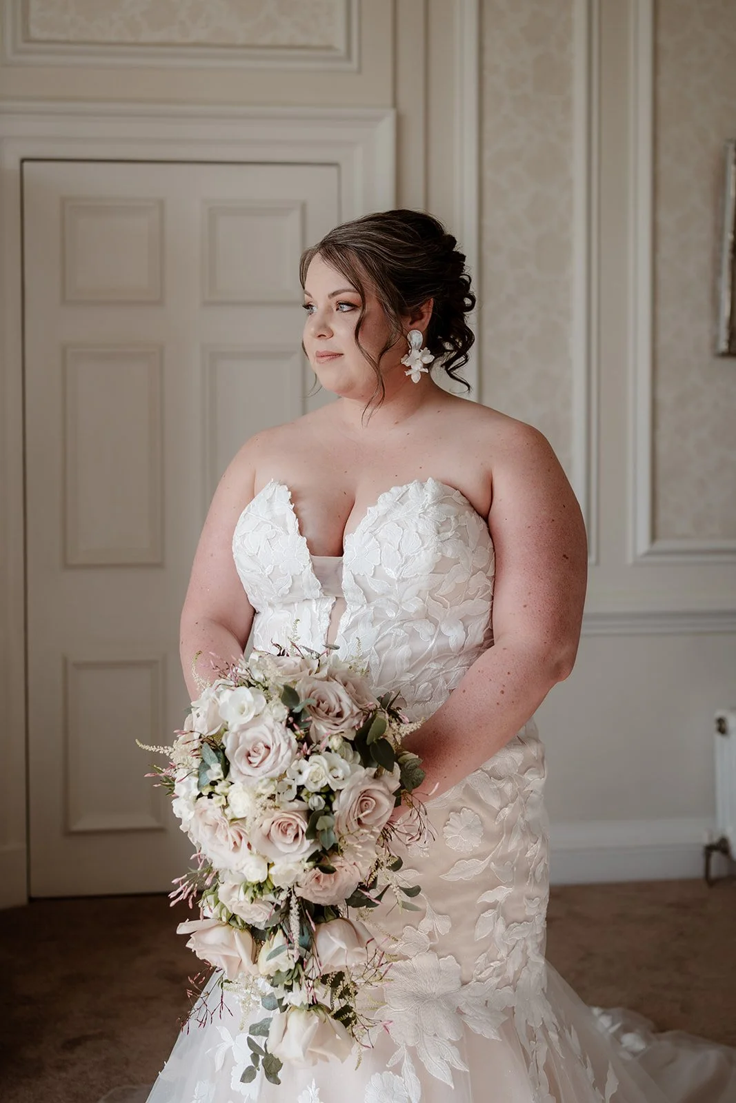 a bride on her wedding day, wearing a white wedding dress and holding a bridal bouquet