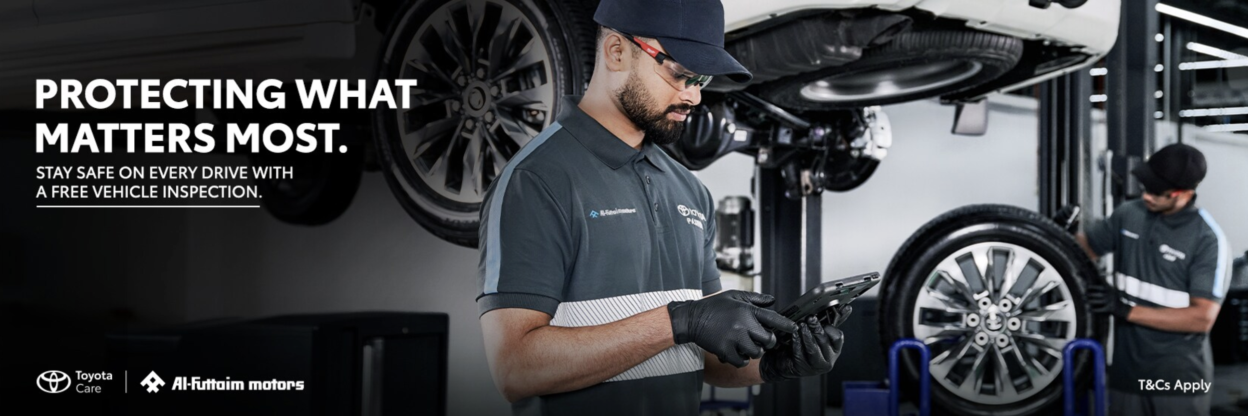 Toyota mechanics inspecting vehicles in a garage, with one mechanic holding a tablet and another working on a car elevated on a lift.