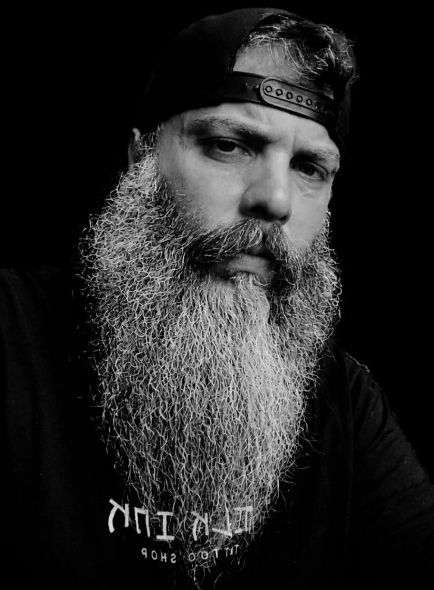 A tattoo artist with curly hair and tattoos on his arm working on a tattoo in a tattoo studio.