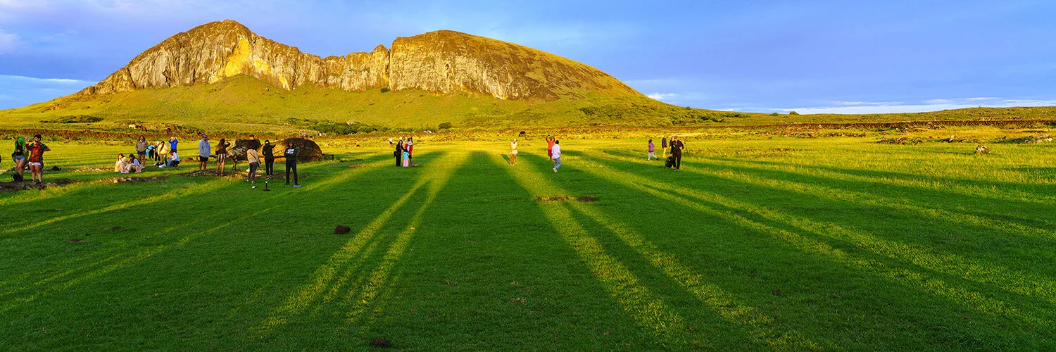  Sunrise shadows of moai at Tongariki with tourists and quarry (Rano Raraku) in distance on Easter Island. 