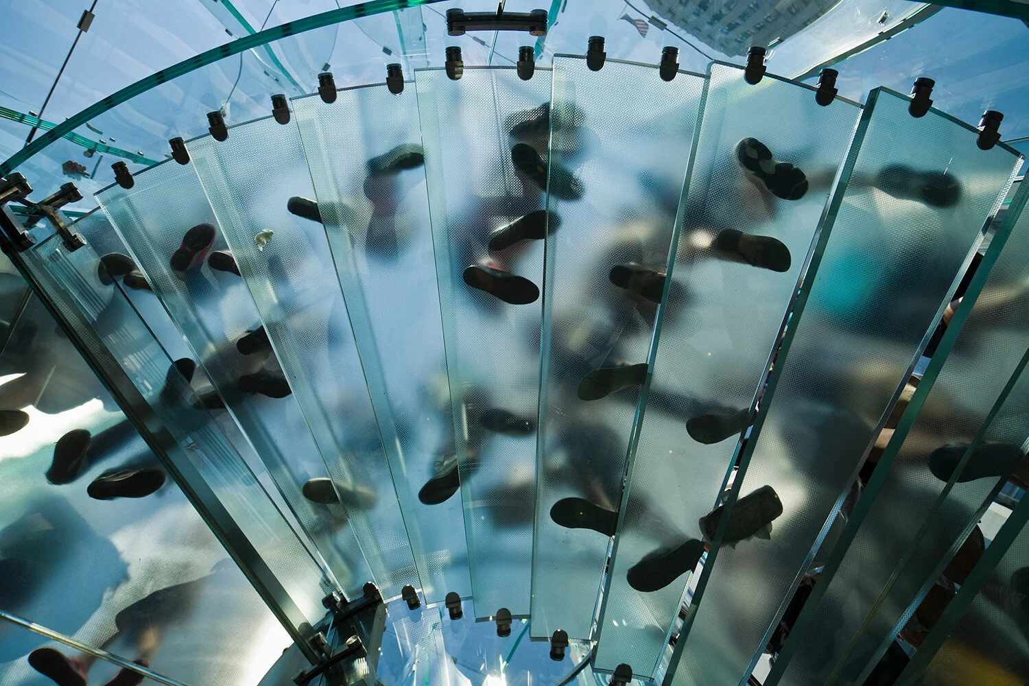  Looking up at soles of souls on glass staircase in New York City. 