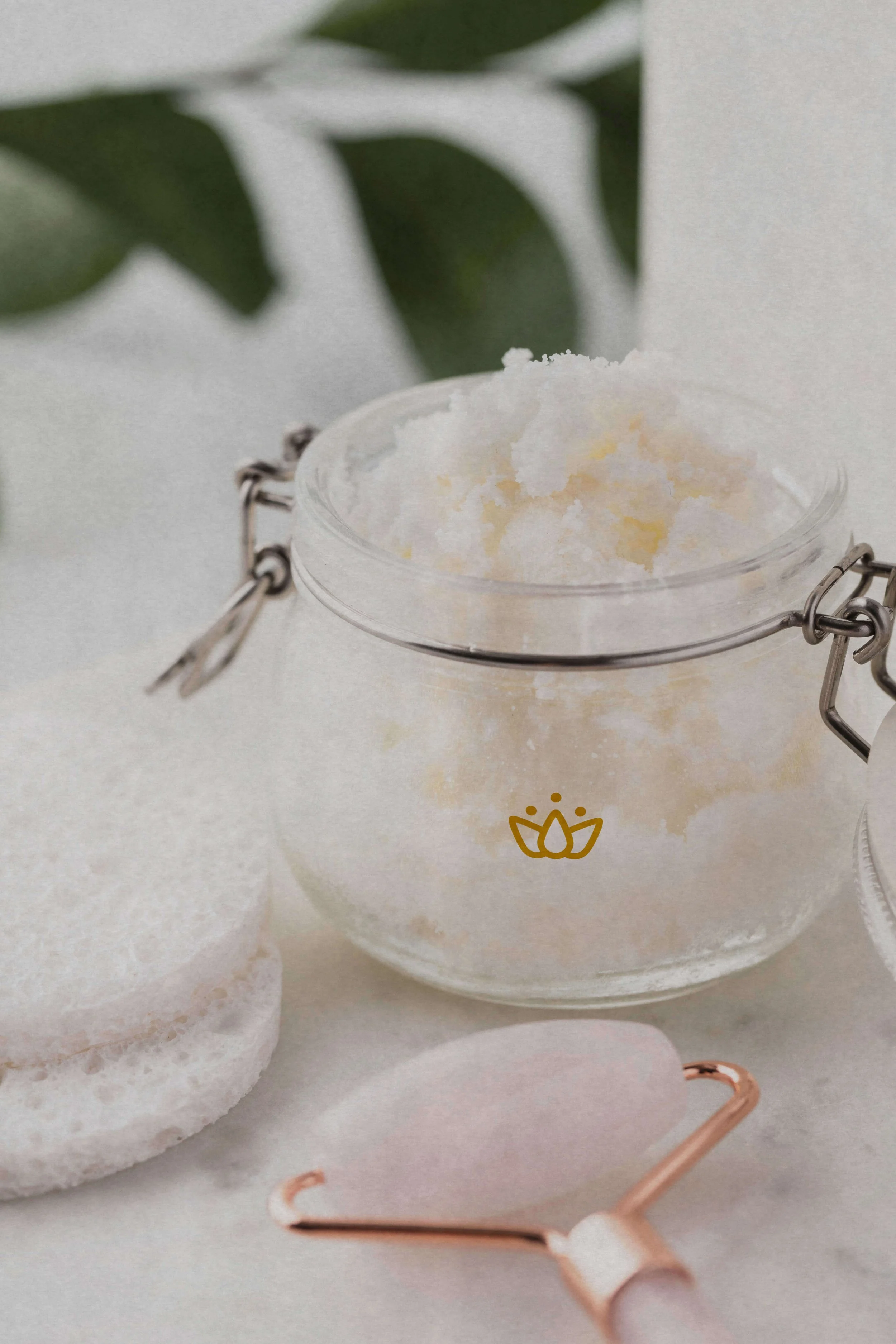 Glass jar of scrub with a rose quartz face roller.