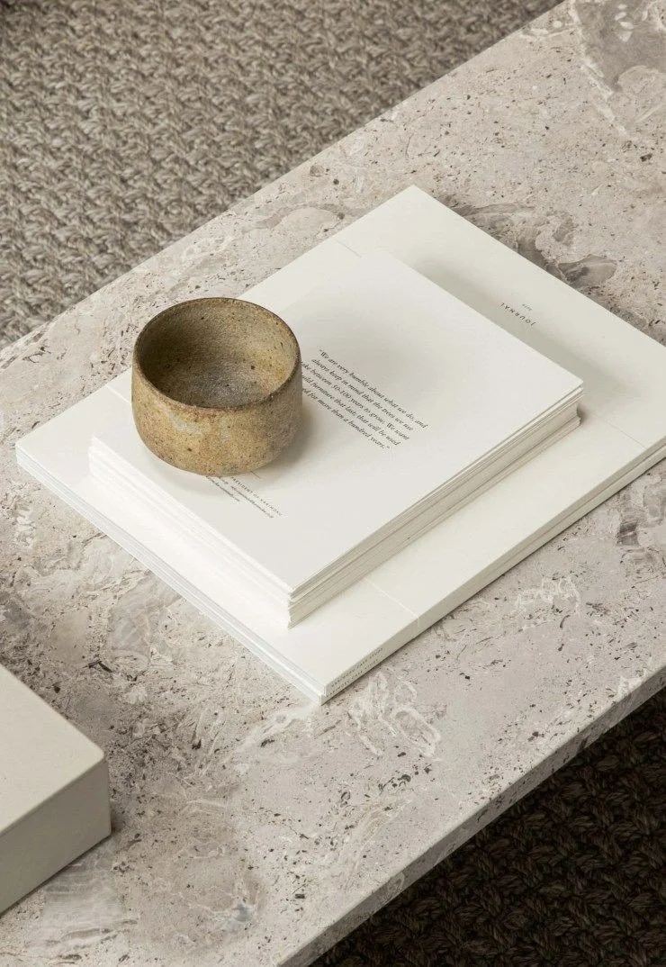 Curation of art and design books on a marble surface with artisanal ceramic, symbolizing intentional design and brand strategy for wellness professionals and visionary creatives.