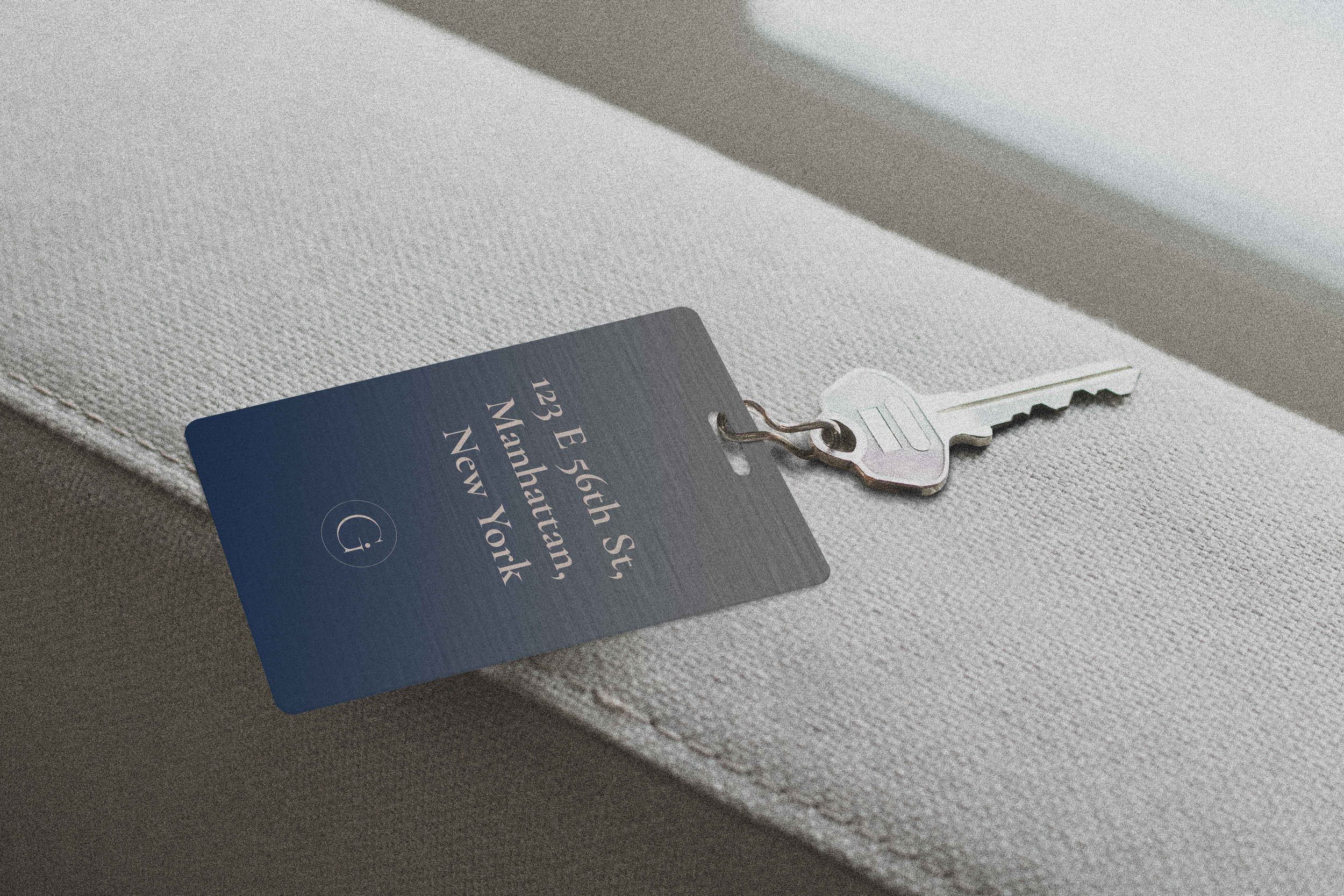 Metal key tag with Manhattan address on a textured surface.