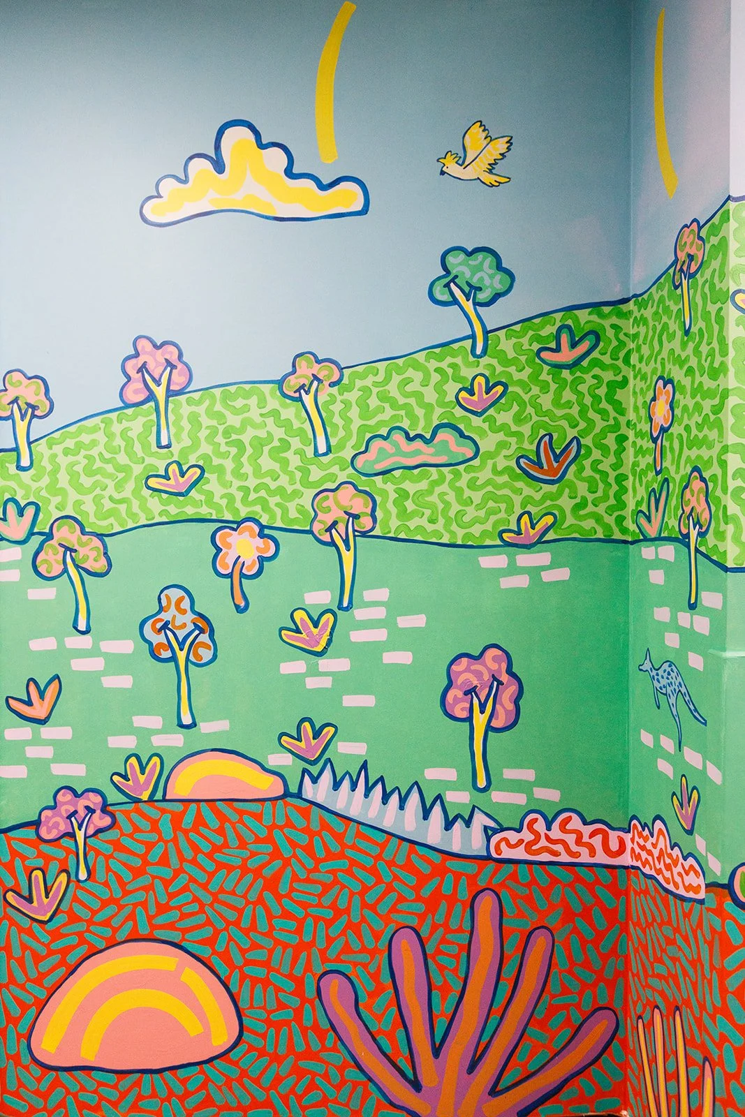 Detail of a colourful Australian landscape mural by Kat Tillman featuring native-inspired trees, plants, a bird and kangaroo in Churchill, Victoria.