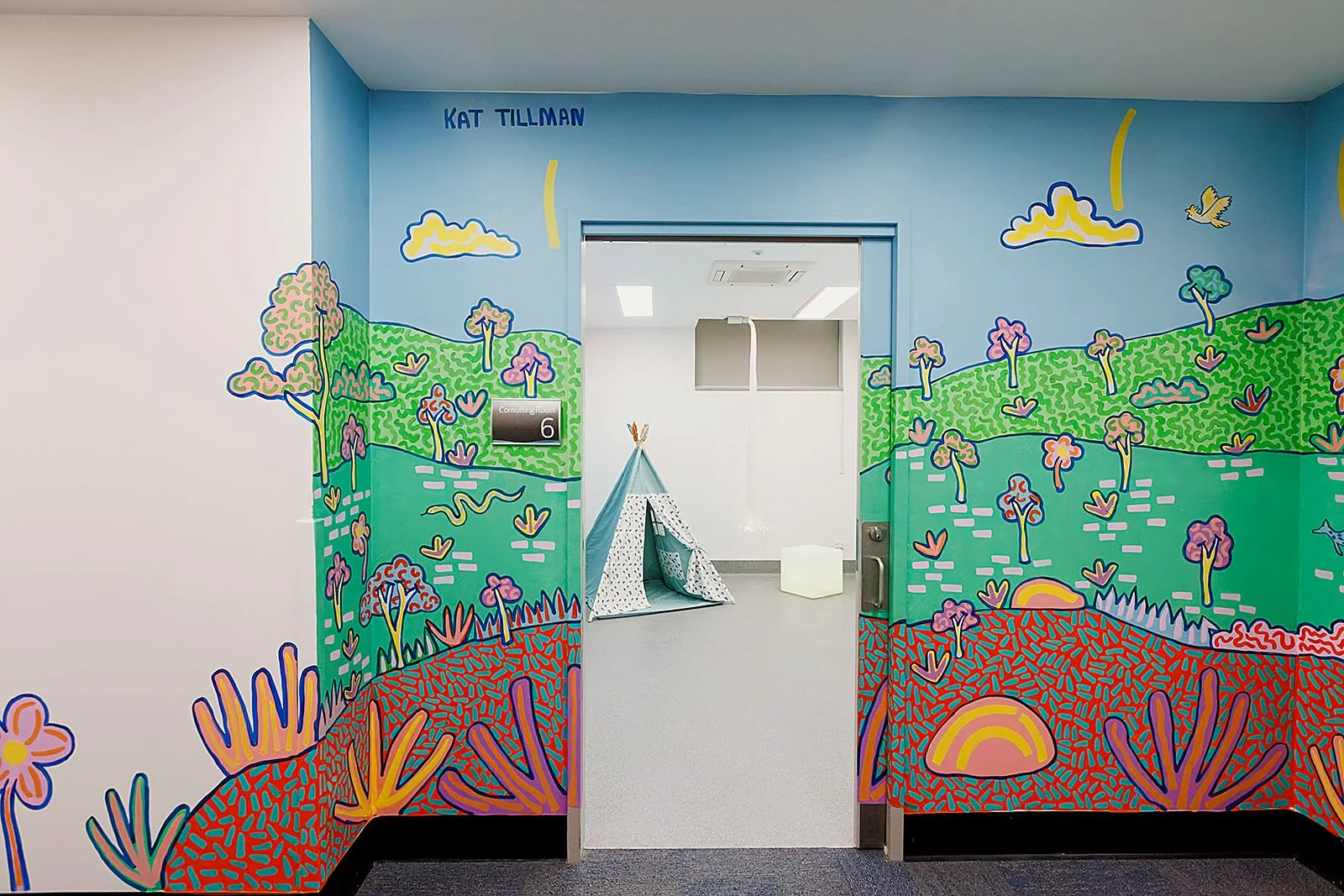 Large-scale hallway mural by Melbourne mural artist Kat Tillman, featuring a colourful Australian landscape at Latrobe Community Health Service.