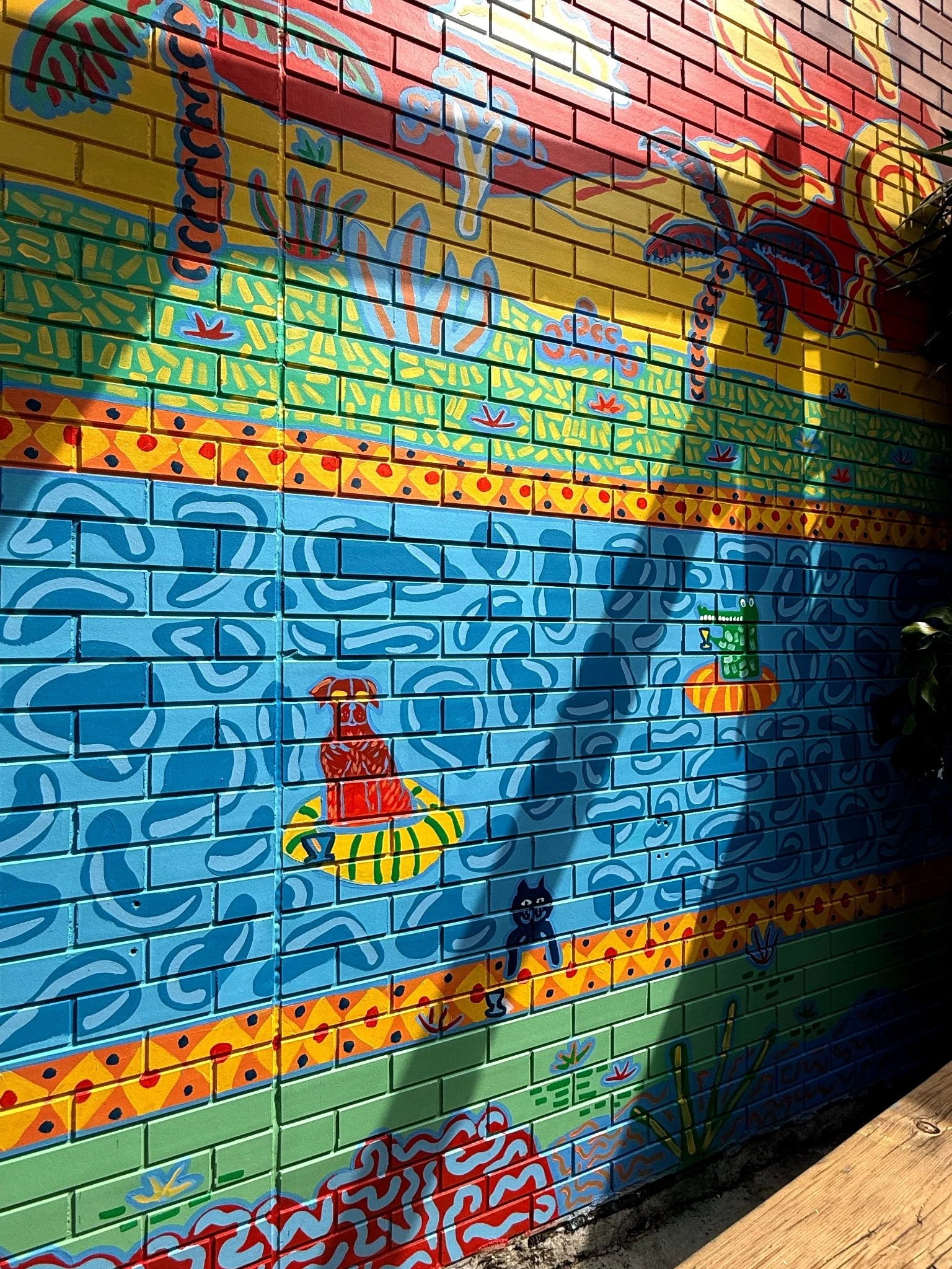 Colourful courtyard mural detail by Melbourne mural artist Kat Tillman, featuring a playful swimming pool and tropical landscape.