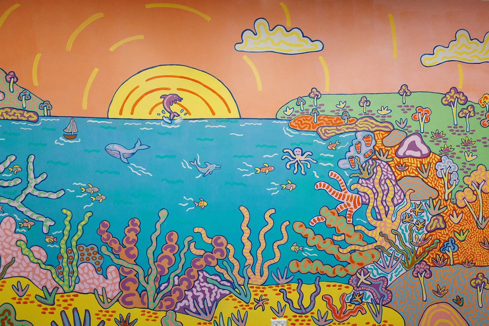 Colourful underwater mural by Kat Tillman featuring coral, sea life, whales, fish and a sunset at Latrobe Community Health Service.