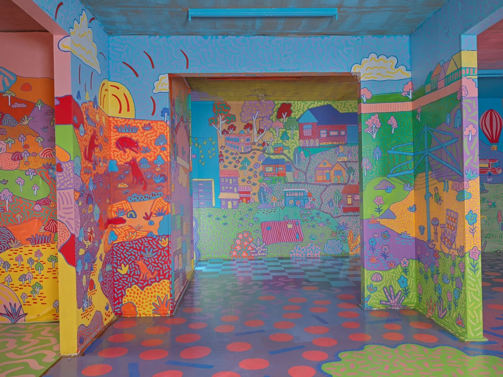 View through the brightly painted rooms of the Side Quest Stories house in Warrandyte, showcasing immersive murals, bold colours and geometric floor patterns.