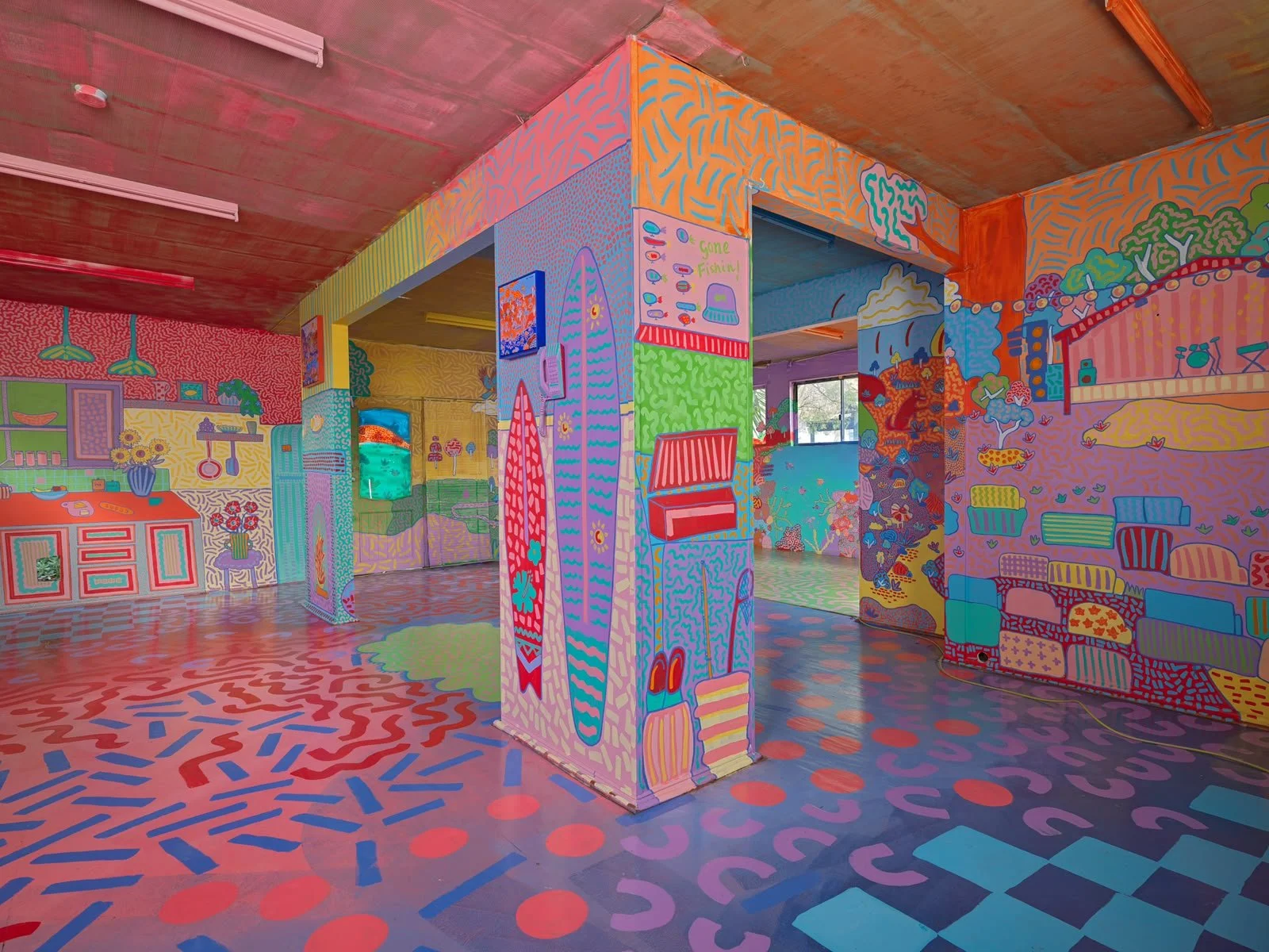 Colourful floor-to-ceiling mural by Melbourne artist Kat Tillman inside the Side Quest Stories house in Warrandyte, featuring playful illustrations, vibrant patterns and painted pillars.