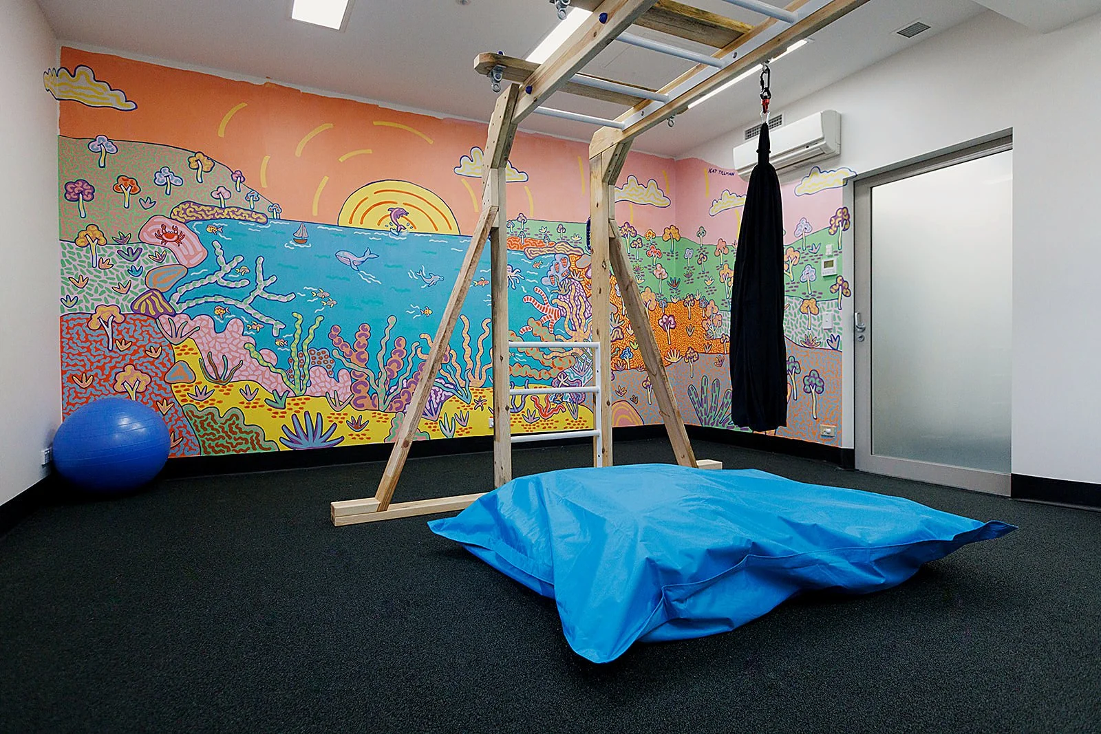 Colourful underwater and Australian landscape mural by Kat Tillman in a children’s play and therapy room at Latrobe Community Health Service.