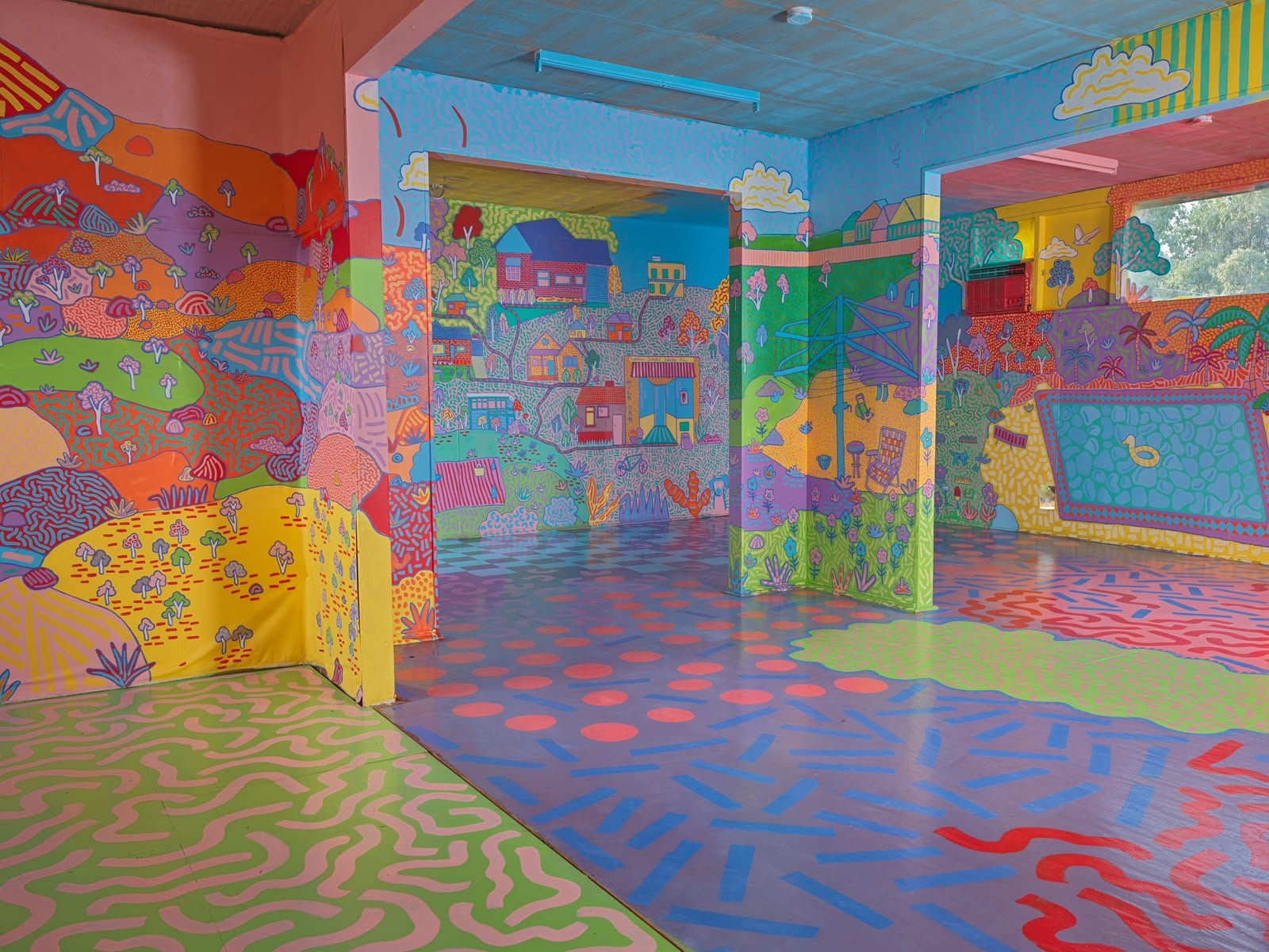 Wide interior view of Kat Tillman's immersive house mural in Warrandyte, featuring vibrant illustrated landscapes, painted columns and colourful patterned floors.
