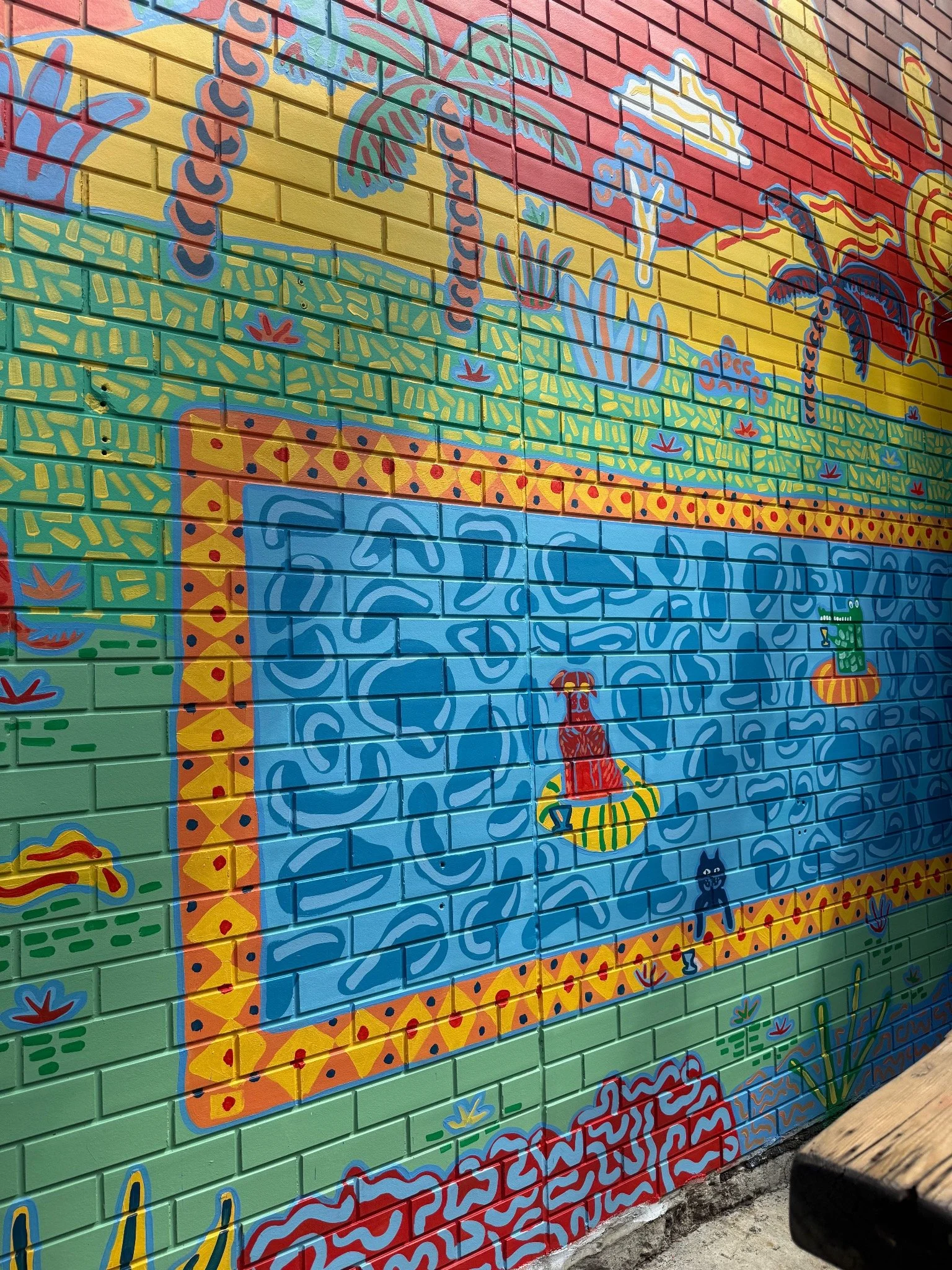 Playful swimming pool scene within a colourful courtyard mural by Melbourne mural artist Kat Tillman.