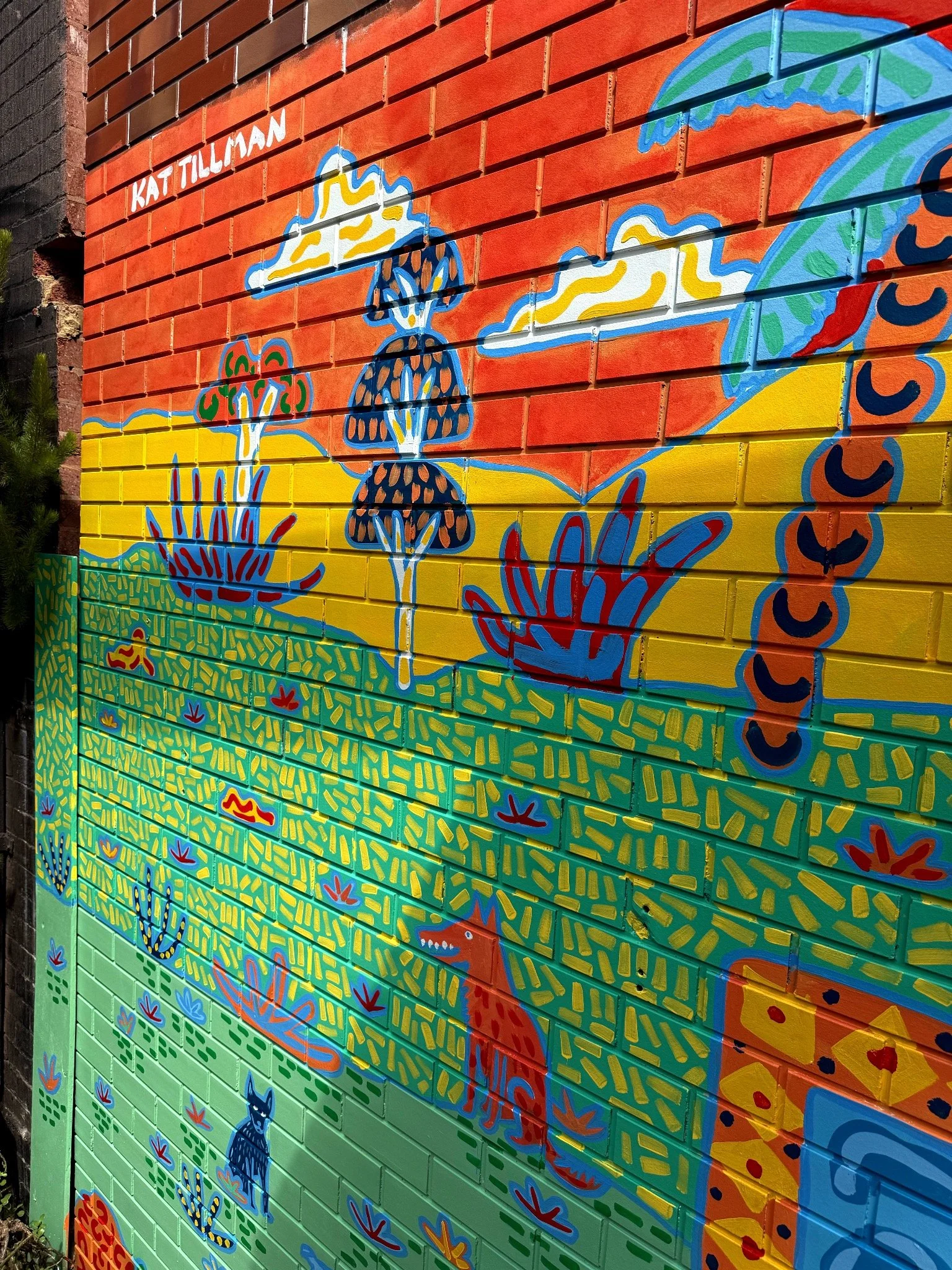 Detail of a colourful Australian landscape mural by Melbourne artist Kat Tillman, painted on an outdoor brick wall.