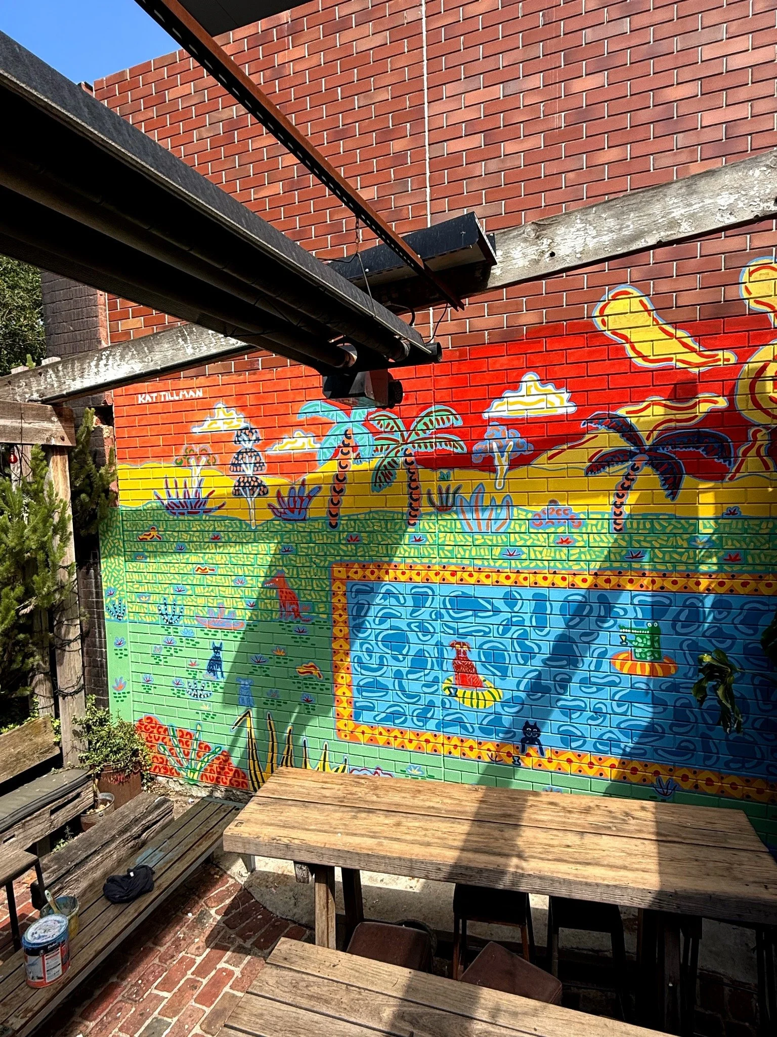 Large-scale colourful courtyard mural by Melbourne artist Kat Tillman, painted across a brick wall in Fitzroy.