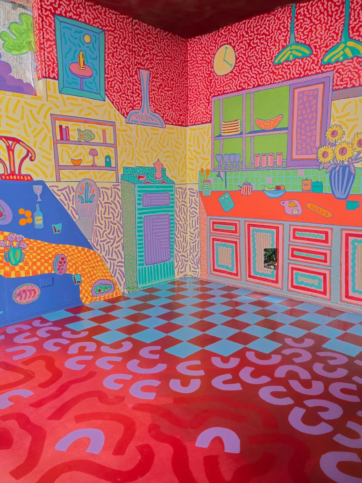 Brightly coloured mural depicting a playful domestic interior with illustrated furniture, windows and everyday objects, part of the Side Quest Stories project.