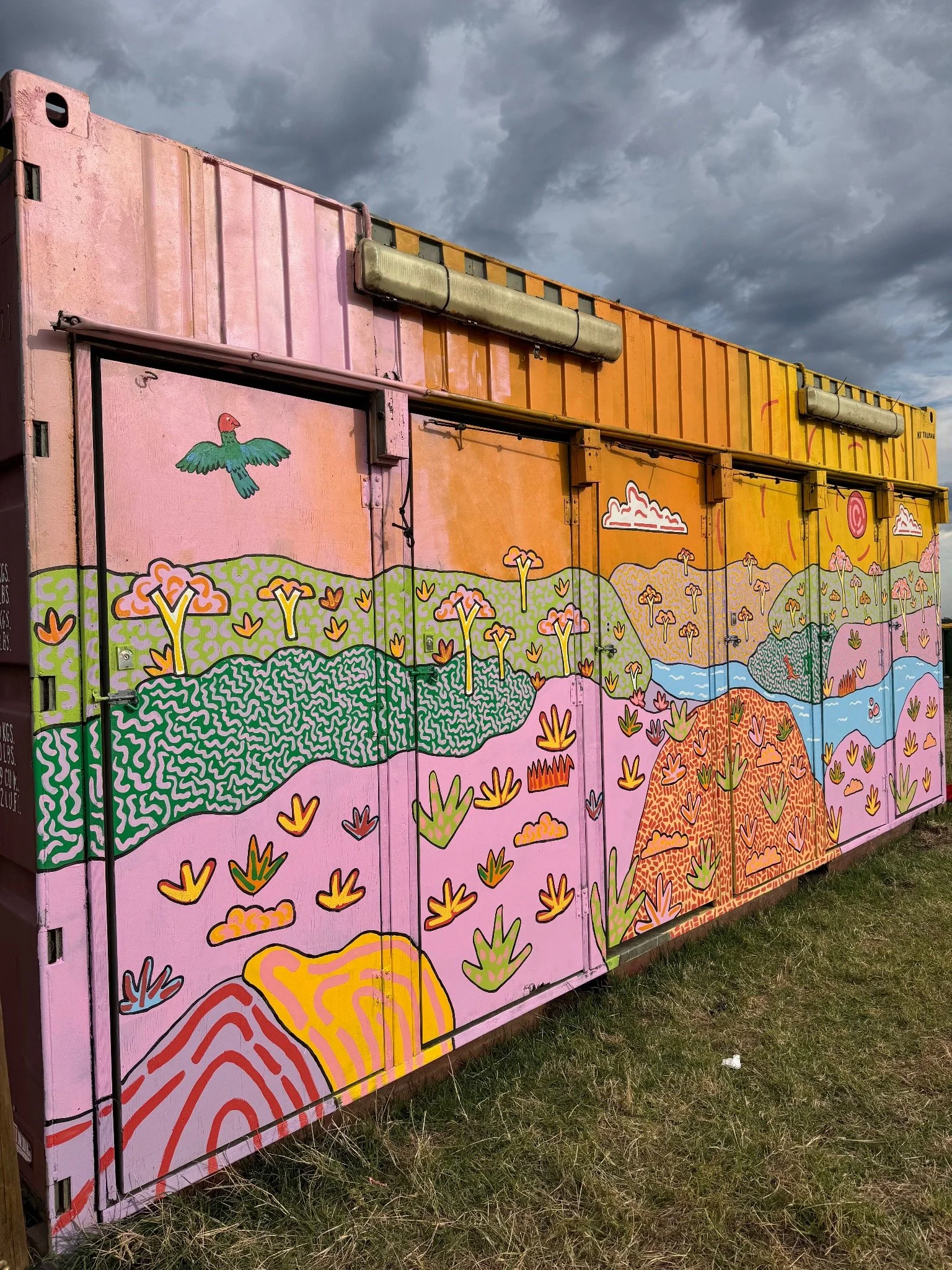 Angled view of Kat Tillman’s colourful container mural featuring rolling Australian hills, native plants, trees and waterways.