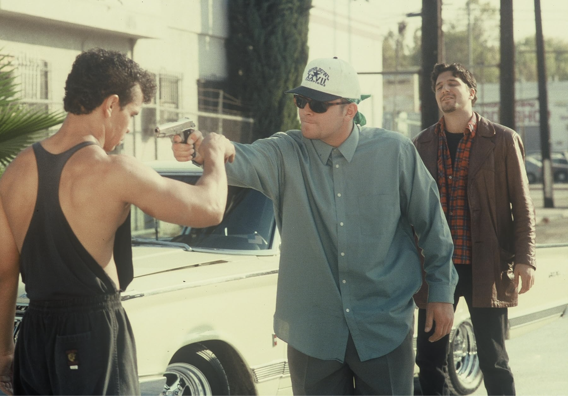 A martial artist grabs the wrist of an armed man during a street confrontation in City Dragon (1995).