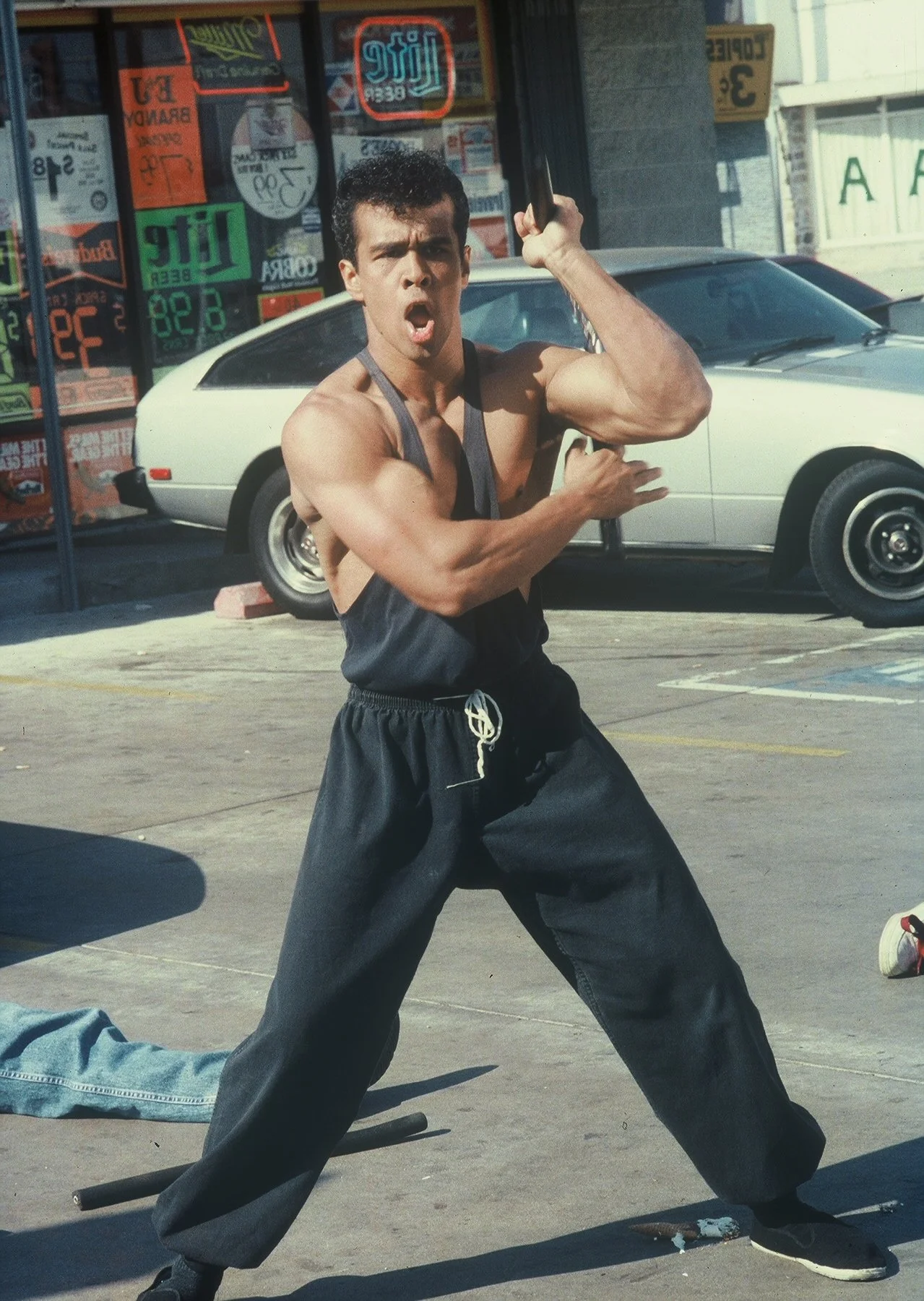 The hero of City Dragon (1995) strikes a martial-arts pose outside a convenience store.