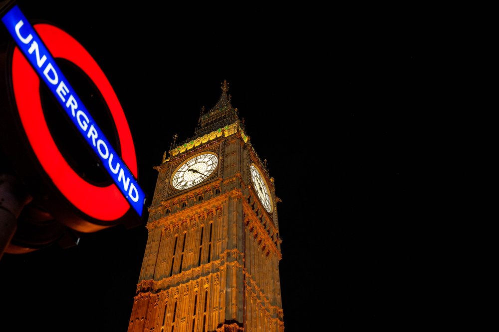 Der Elizabeth Tower bzw. Big Ben mit dem roten Underground Schild im Vordergrund bei Nacht