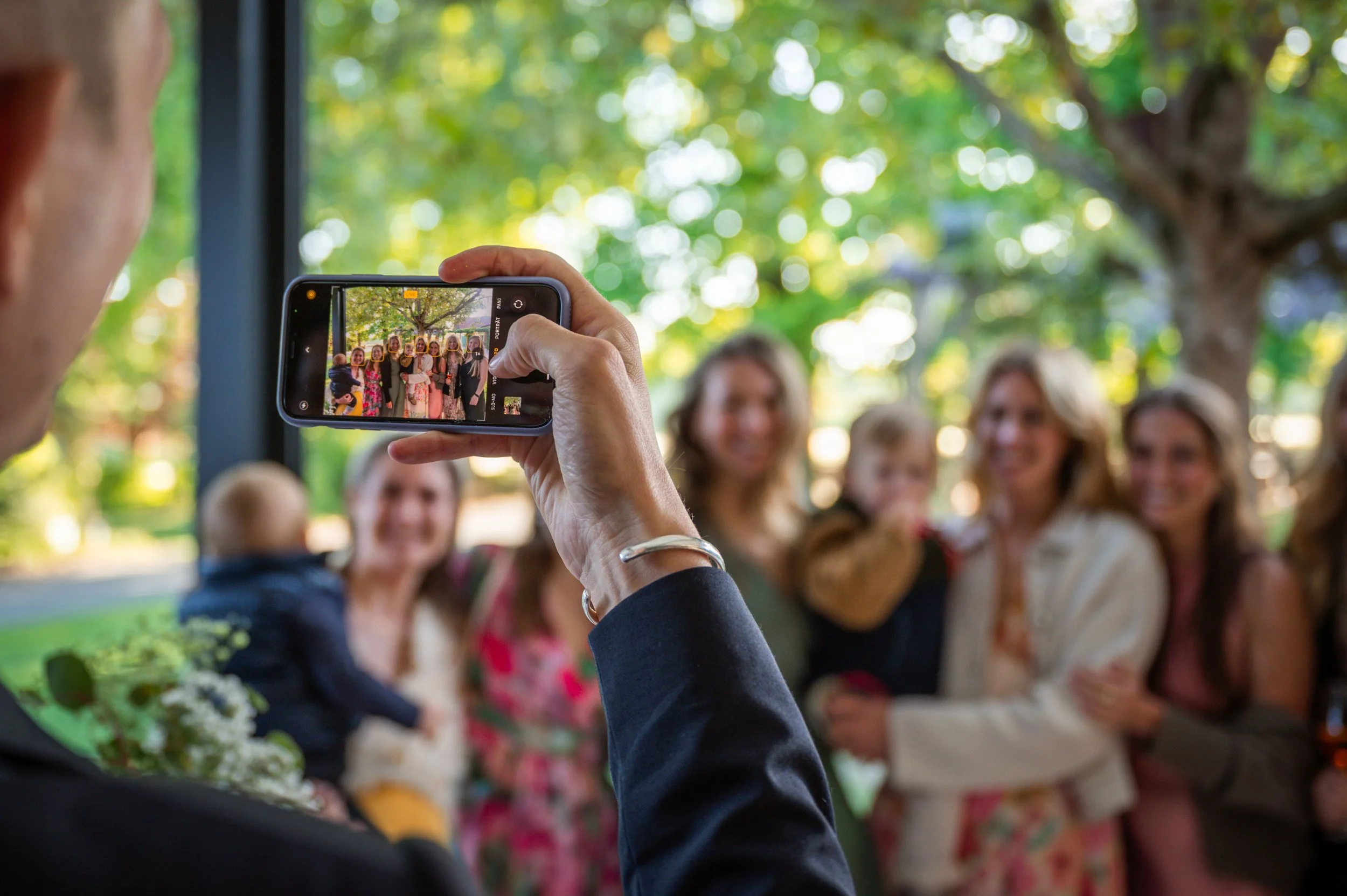 EIn Hochzeitsgast macht ein Foto der Gesellschaft mit dem Handy