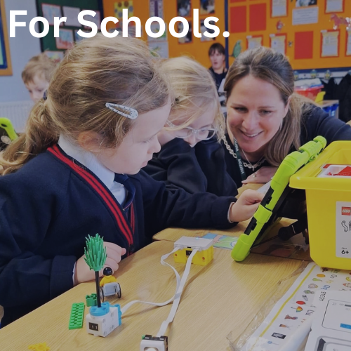 One of our cognition staff is working with two young female students. They have a LEGO education robotics model and green iPad in front of them.