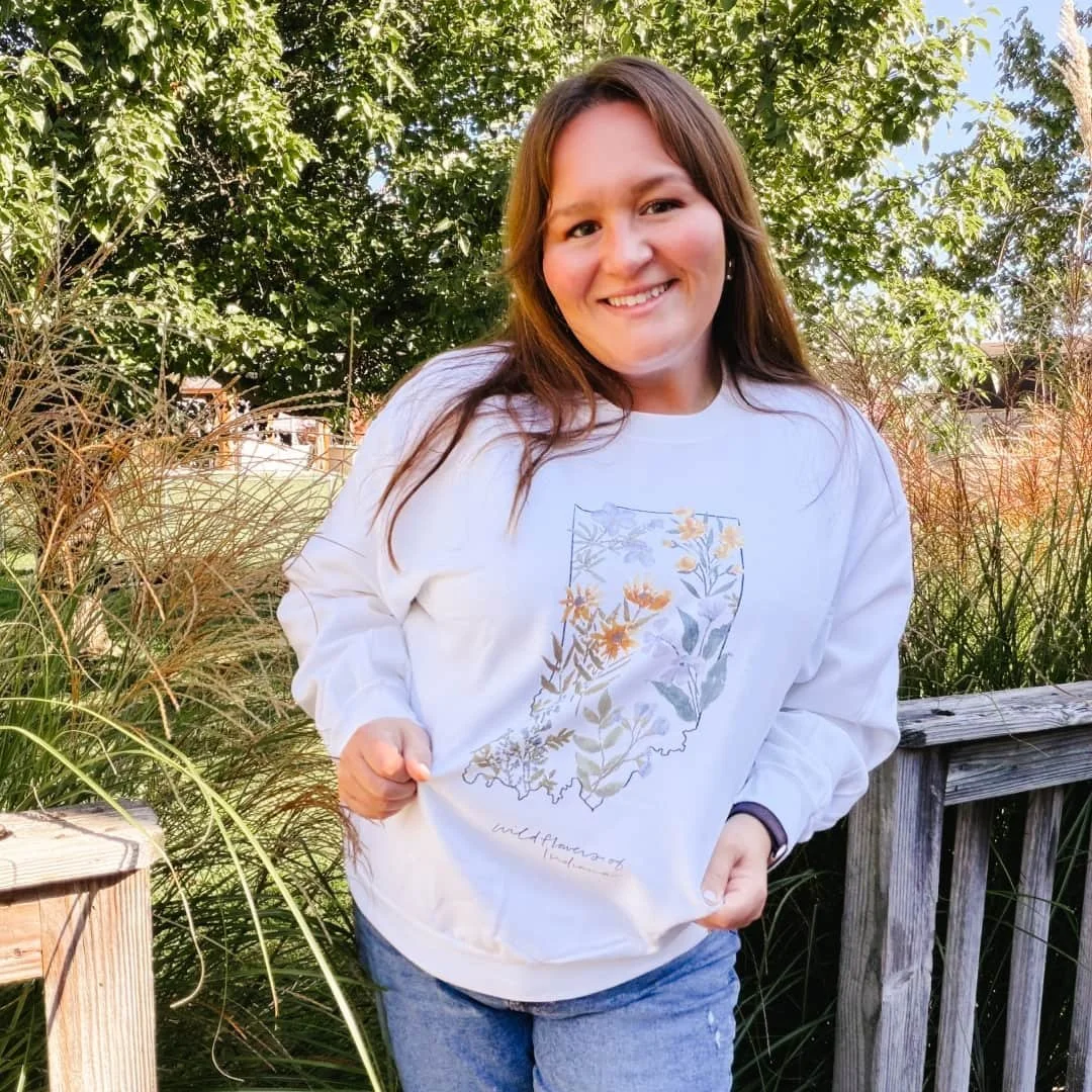Woman outdoors wearing the State of Indiana Wildflowers watercolor crewneck sweatshirt