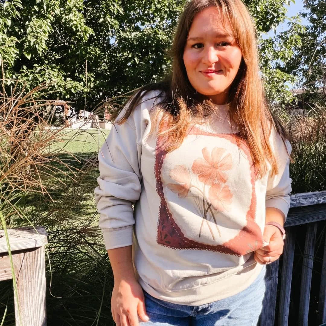 Woman outdoors wearing the Fall Floral watercolor cosmos crewneck sweatshirt