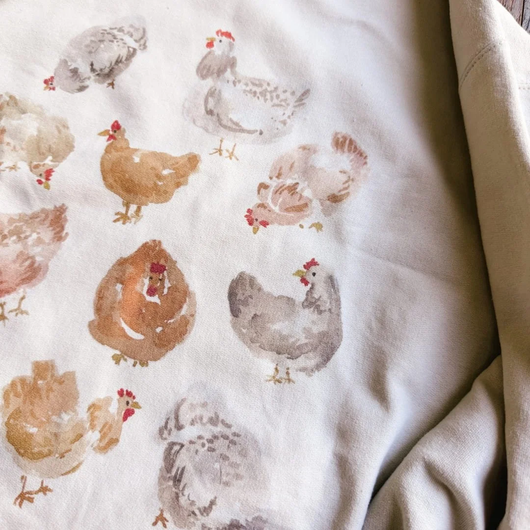 Close-up of hand-painted watercolor hens on the sand crewneck sweatshirt