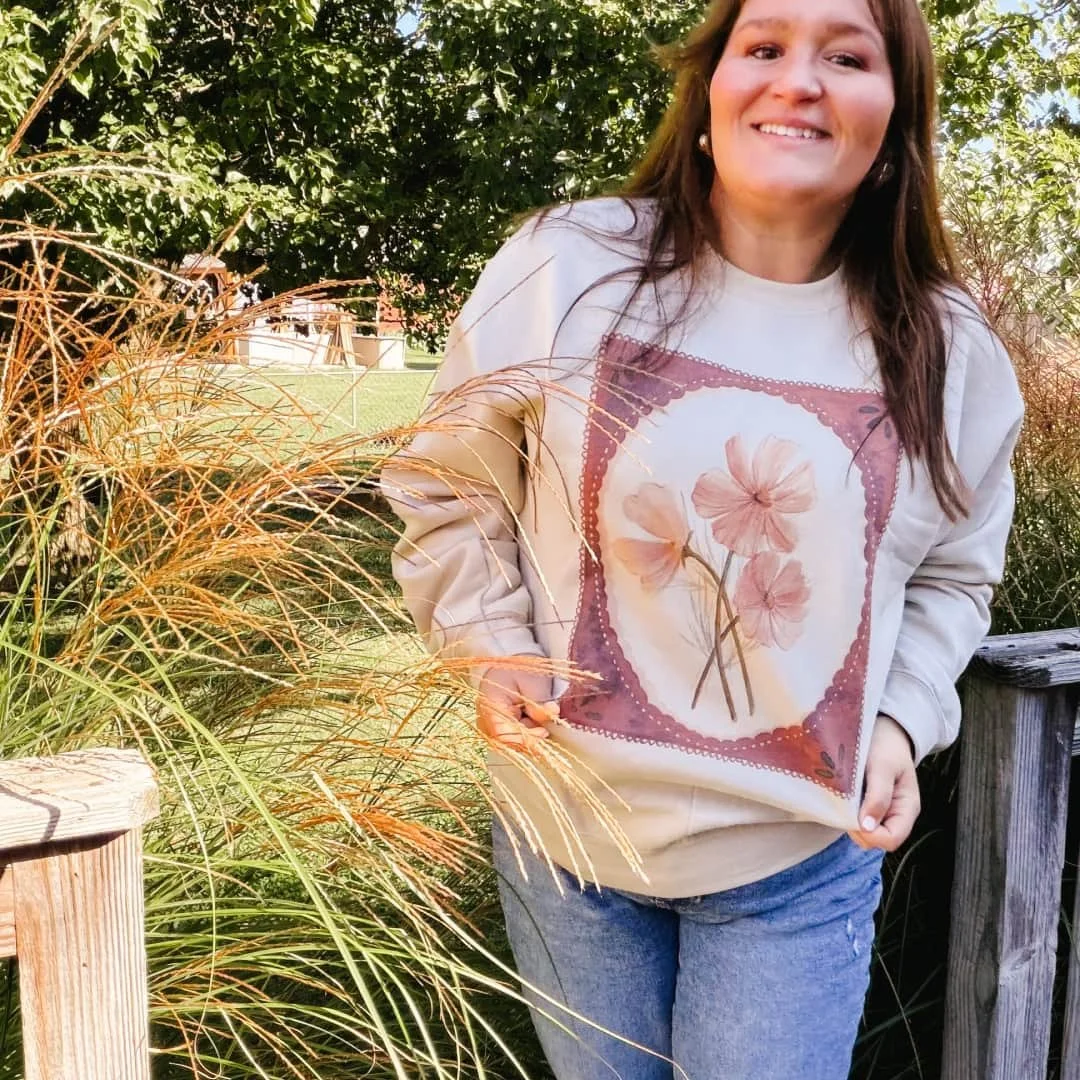 Woman on a deck wearing the Fall Floral cosmos watercolor sweatshirt