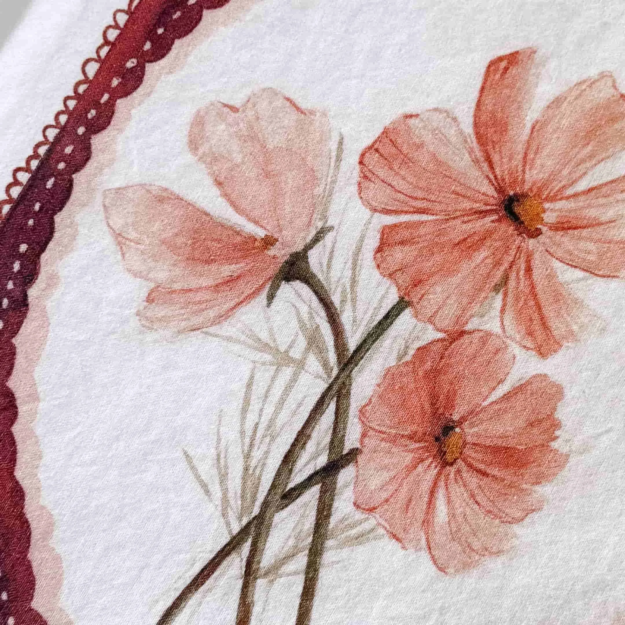 Close-up of watercolor pink cosmos flowers on a handmade tea towel with a scalloped lace-edge border