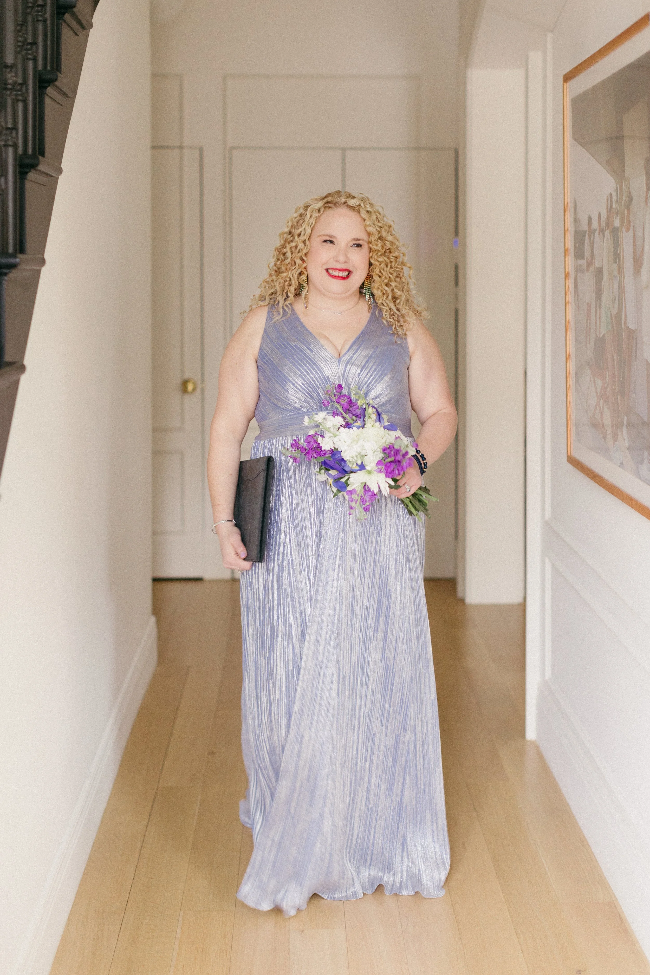 Chicago wedding officiant Carla Doshi holding her ceremony binder and bouquet in an ice blue metallic dress.