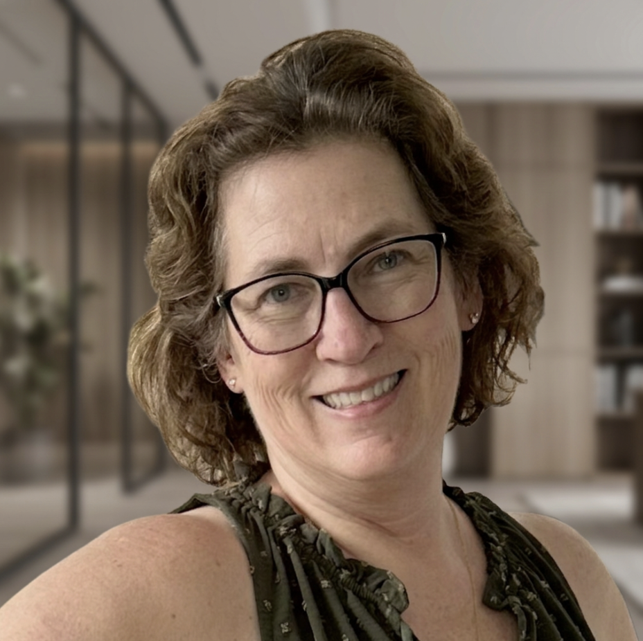 A smiling person with short brown hair and glasses, wearing a red shirt.