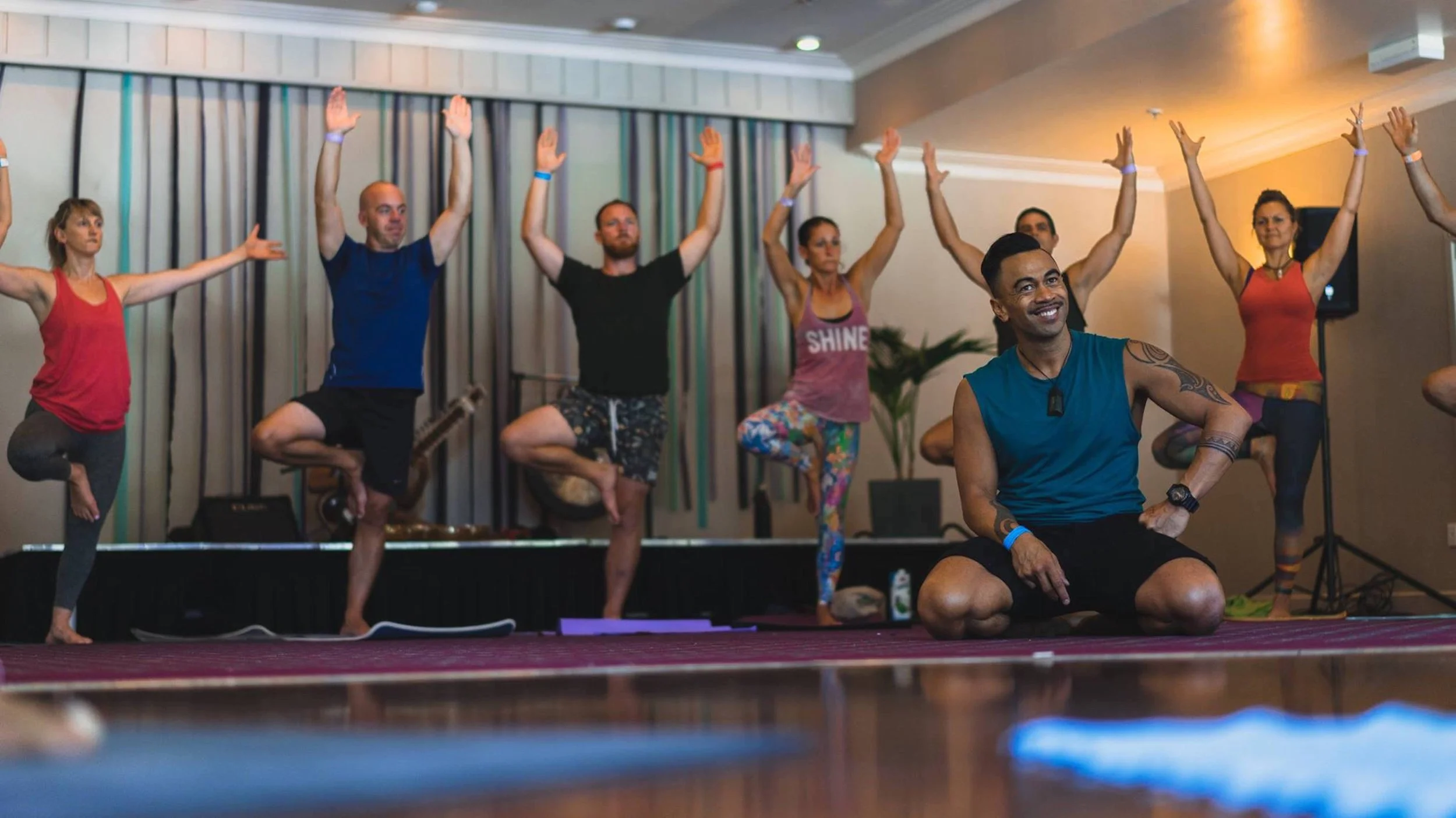 People doing yoga with tutor Jase smiling in front
