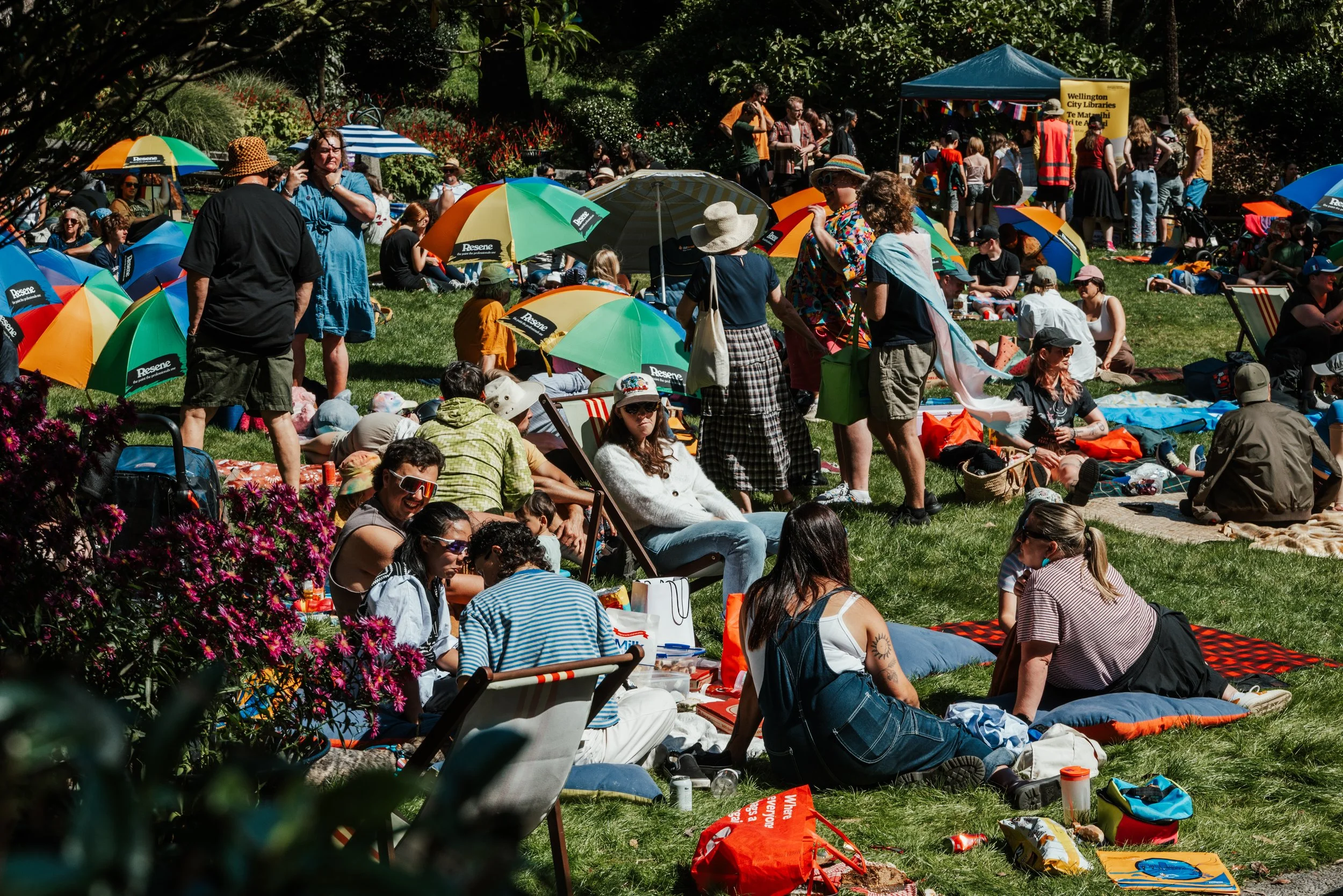People picnic under rainbow umbrellas