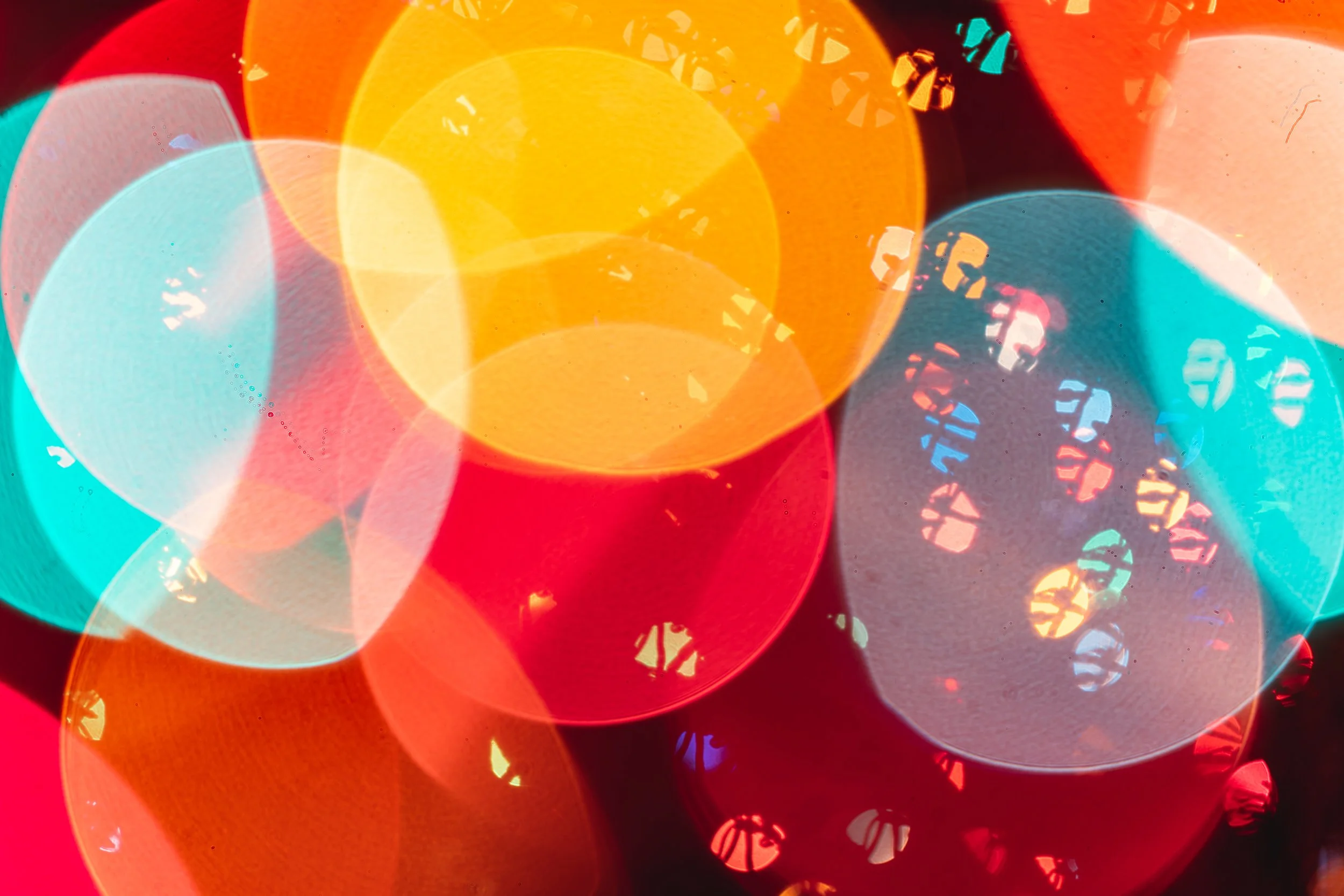 Colorful defocused lights creating a bokeh effect in various sizes and colors, including yellow, red, blue, and orange.