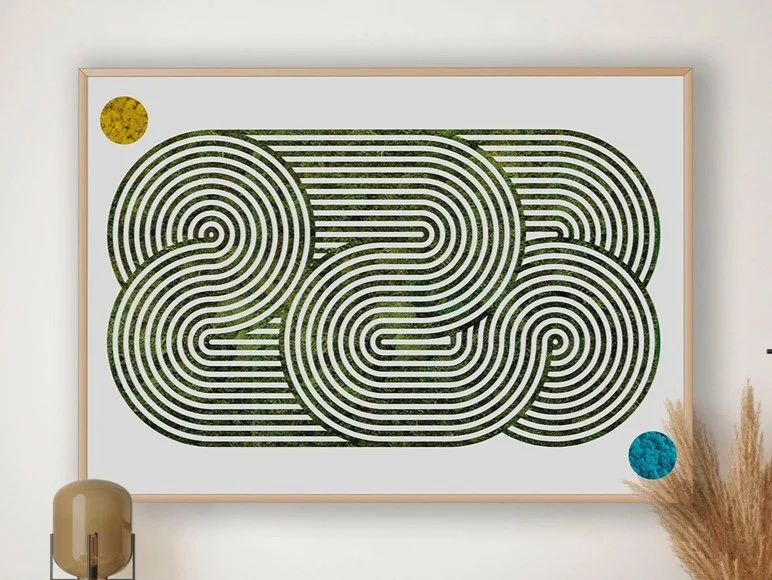 Abstract moss artwork of a maze with two colored circles, one yellow in the top left corner and one blue in the bottom right corner, hanging on a wall.