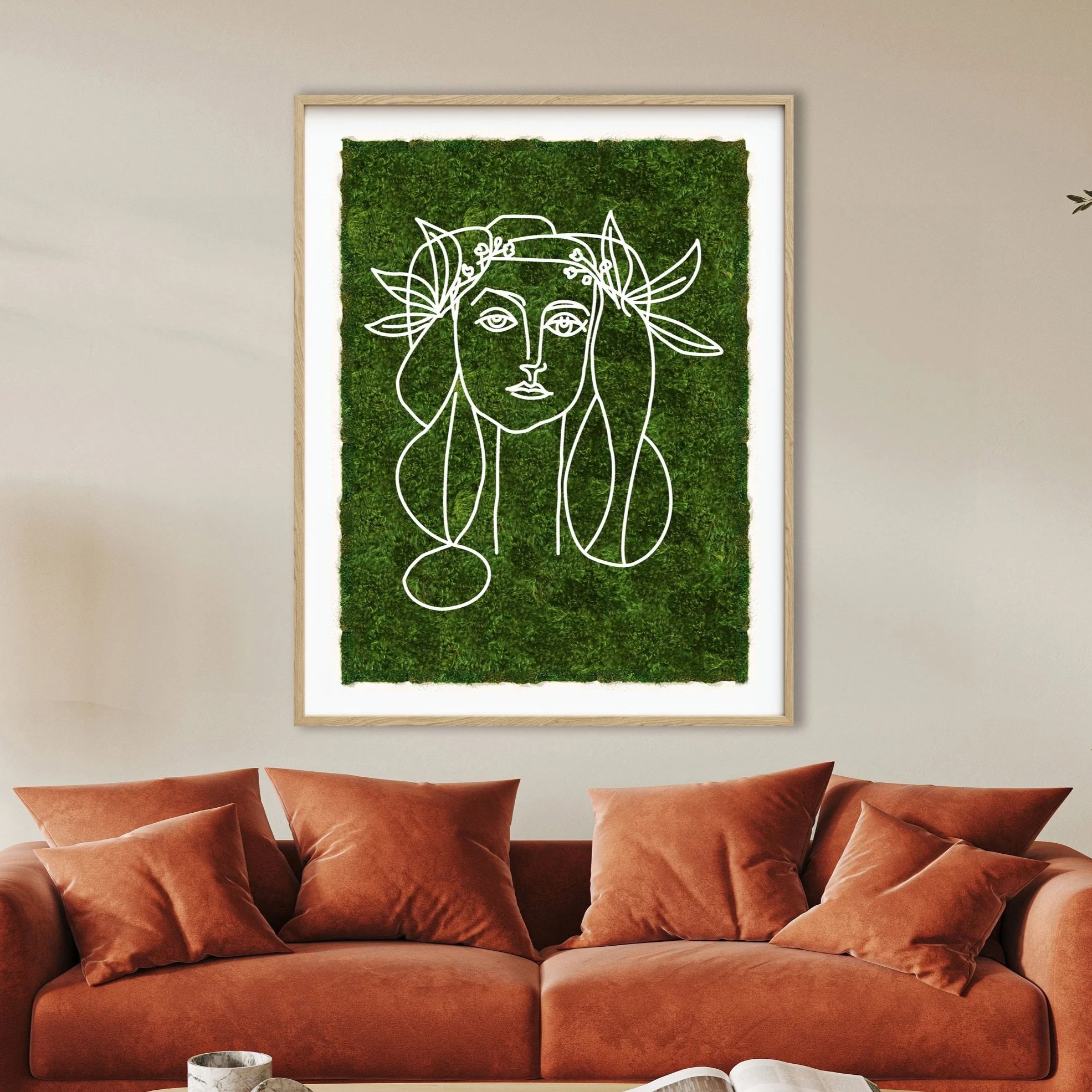 Living room with a rust-colored velvet sofa, matching pillows, and a wall art piece featuring a white line drawing of a woman with leaves and a green textured background.