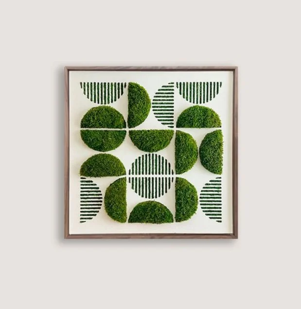 Geometric art piece with green moss and striped patterns arranged in a grid inside a wooden frame.