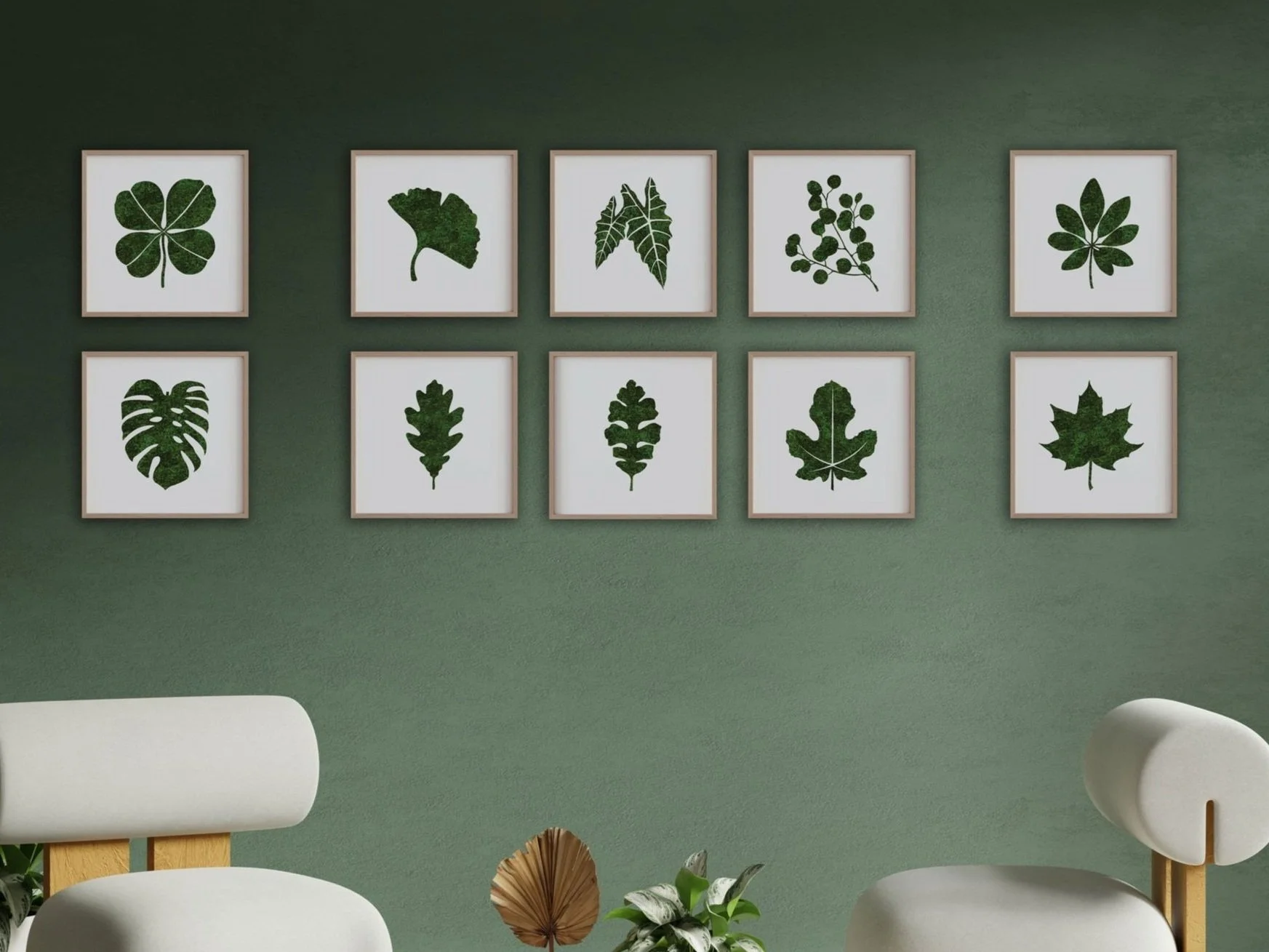 Wall decorated with ten framed botanical preserved moss of different leaf shapes, arranged in two rows of five, on a green wall. Part of white furniture and some plants are visible in the foreground.