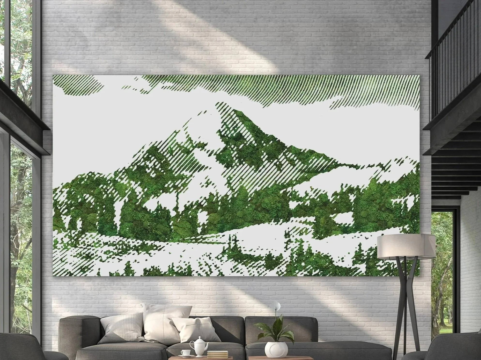 Large preserved moss wall art featuring a mountain landscape with green foliage and snow, situated in a modern living room with a gray sofa, white pillows, and a plant on a wooden coffee table.