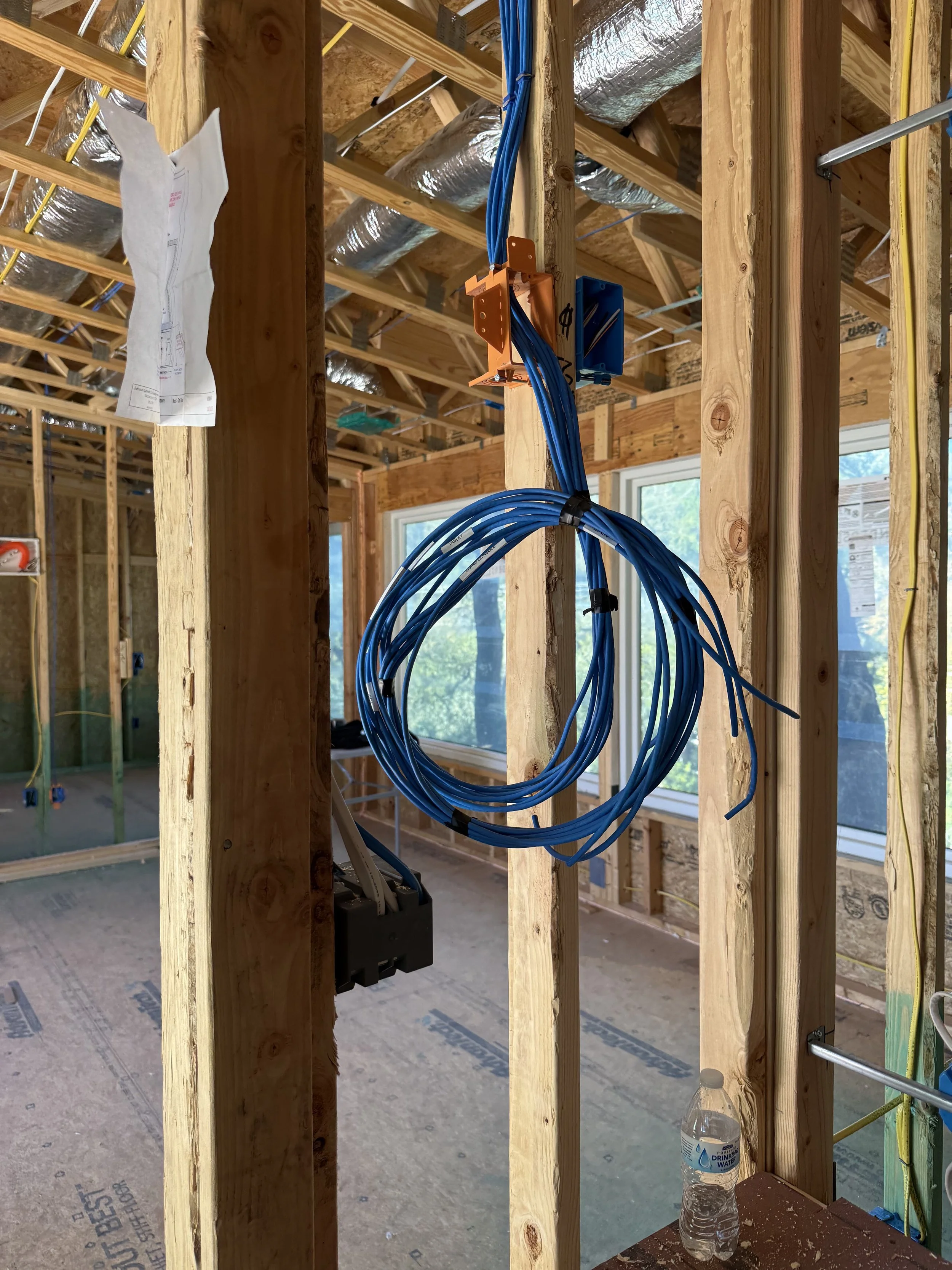 Close-up view of electrical wiring within a wooden framing structure showing blue and white cables secured with black zip ties.