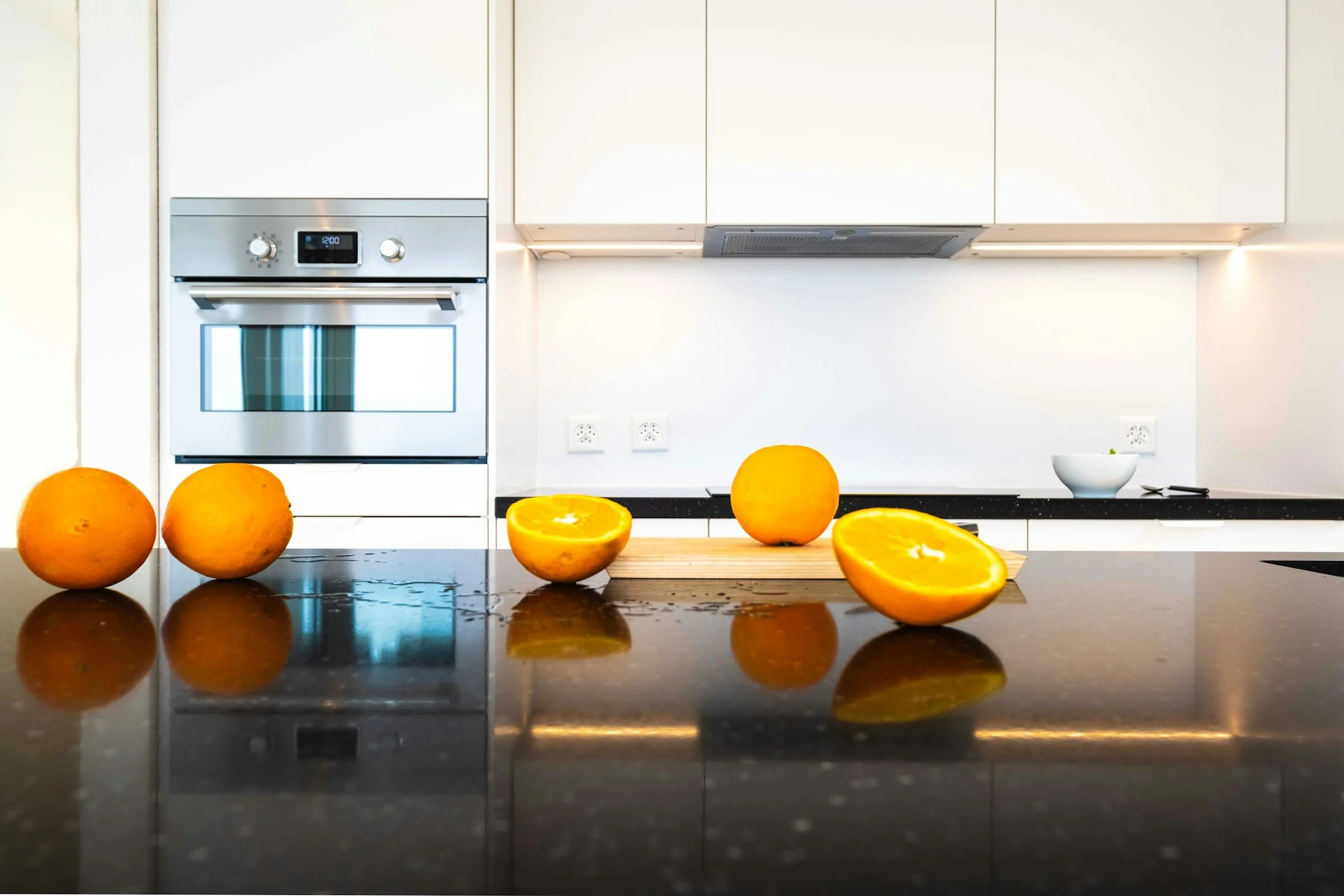 Modern white kitchen renovation with sleek cabinetry, built-in appliances, and black countertops by Michael Moser Contracting in Victoria, BC.
